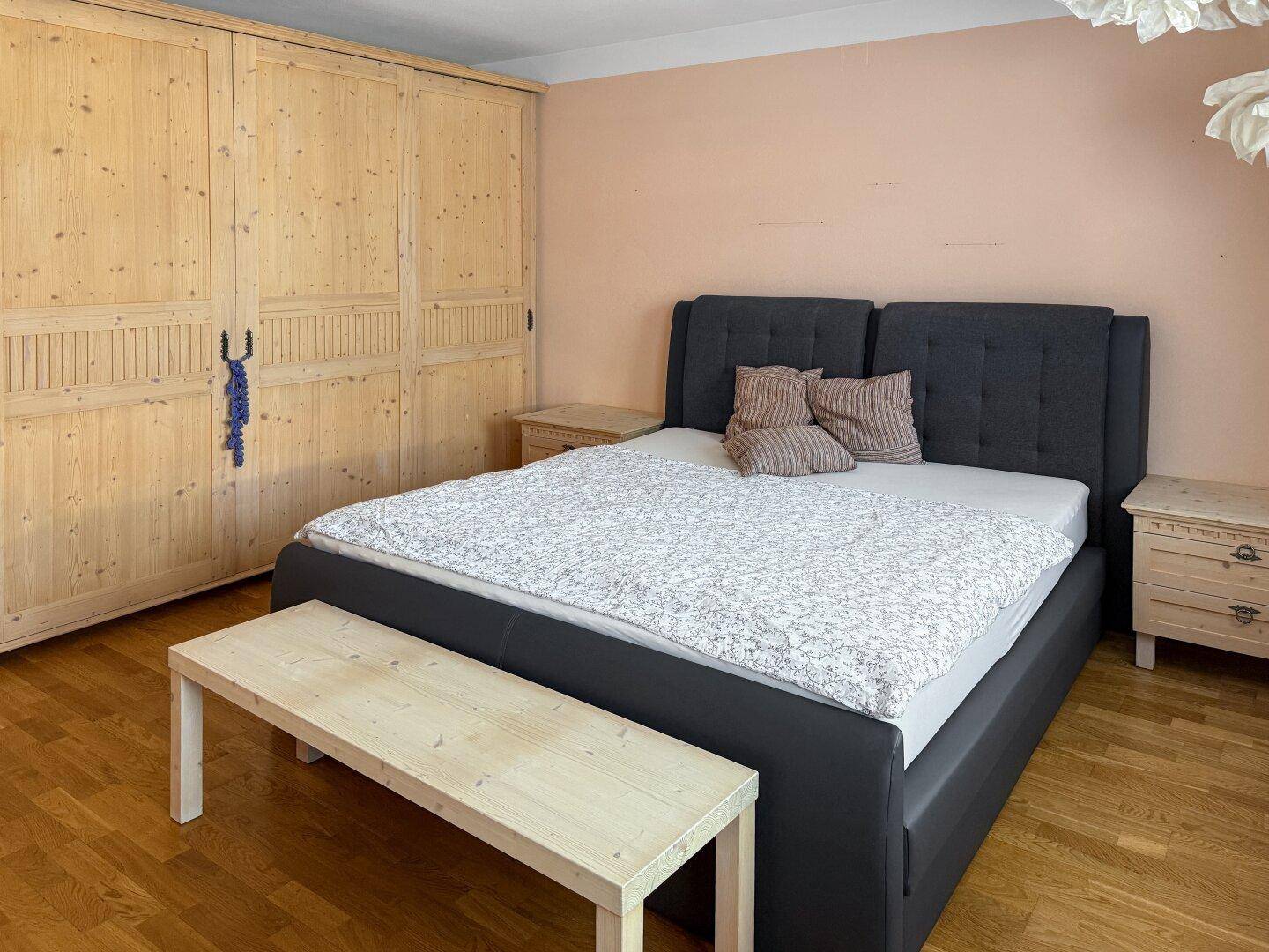 Schlafzimmer mit großem Holzkleiderschrank und Doppelbett.
