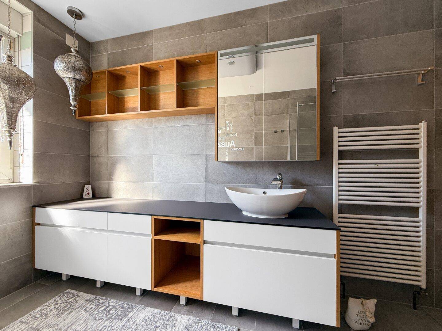 Modernes Badezimmer mit Waschtisch, Aufsatzwaschbecken und beheiztem Handtuchhalter.