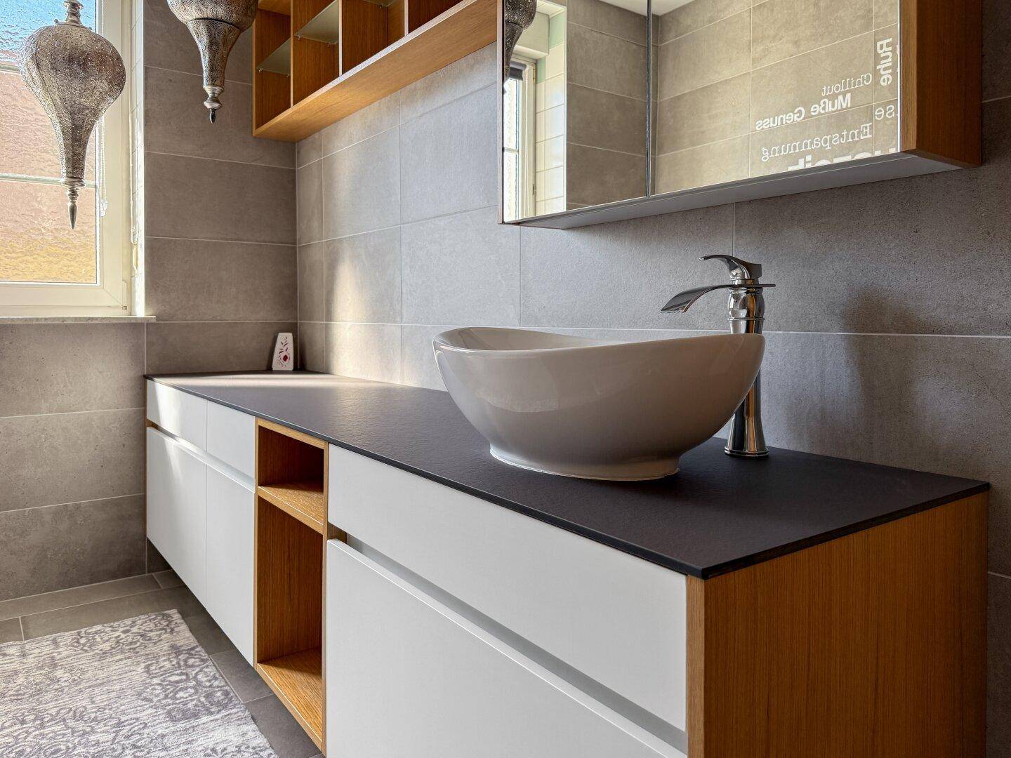 Moderner Waschtisch mit Aufsatzwaschbecken und Spiegel im Badezimmer.