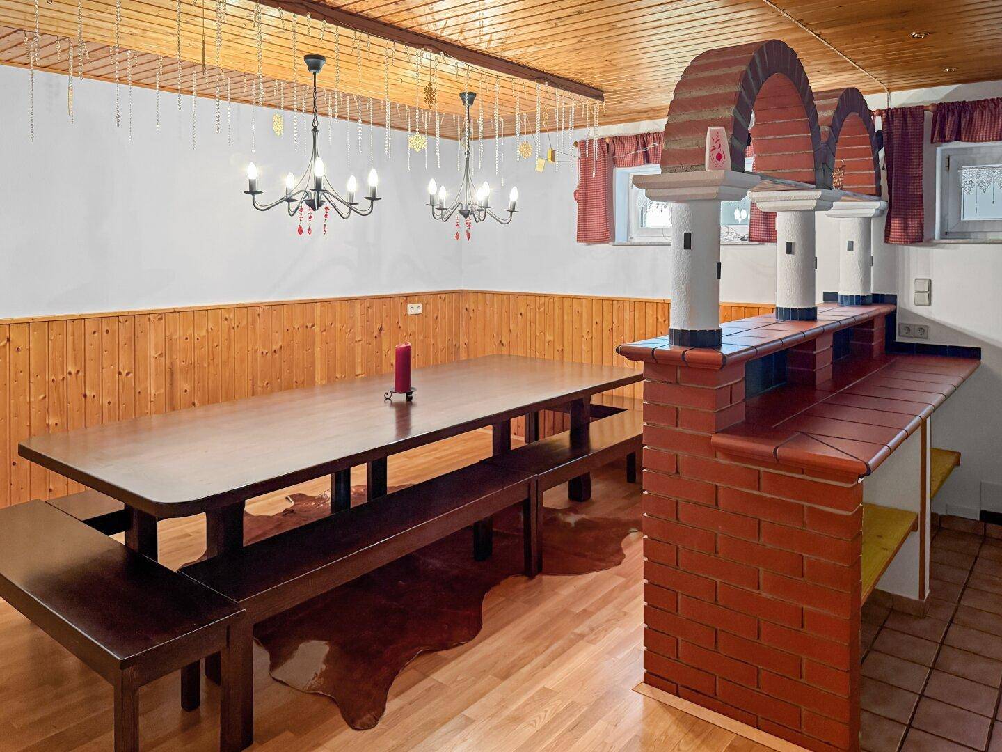 Rustikaler Essbereich mit langem Holztisch, Bänken und gemauerter Bar.