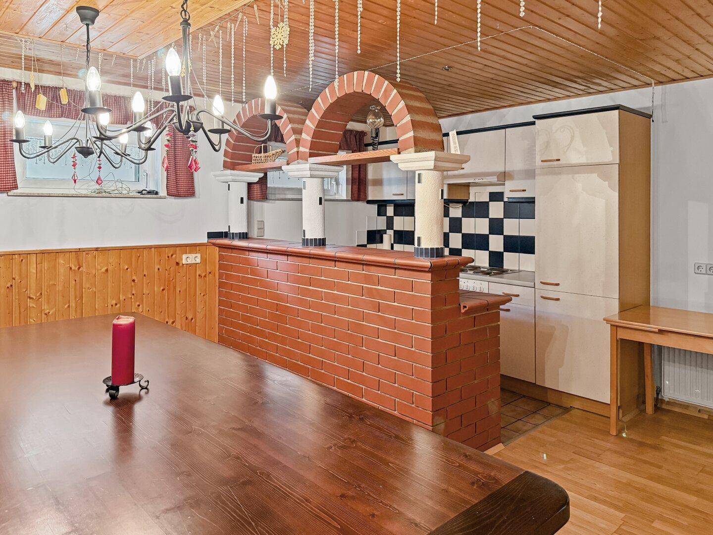 Küche hinter gemauerter Bar mit Arbeitsfläche und traditionellen Fliesen.