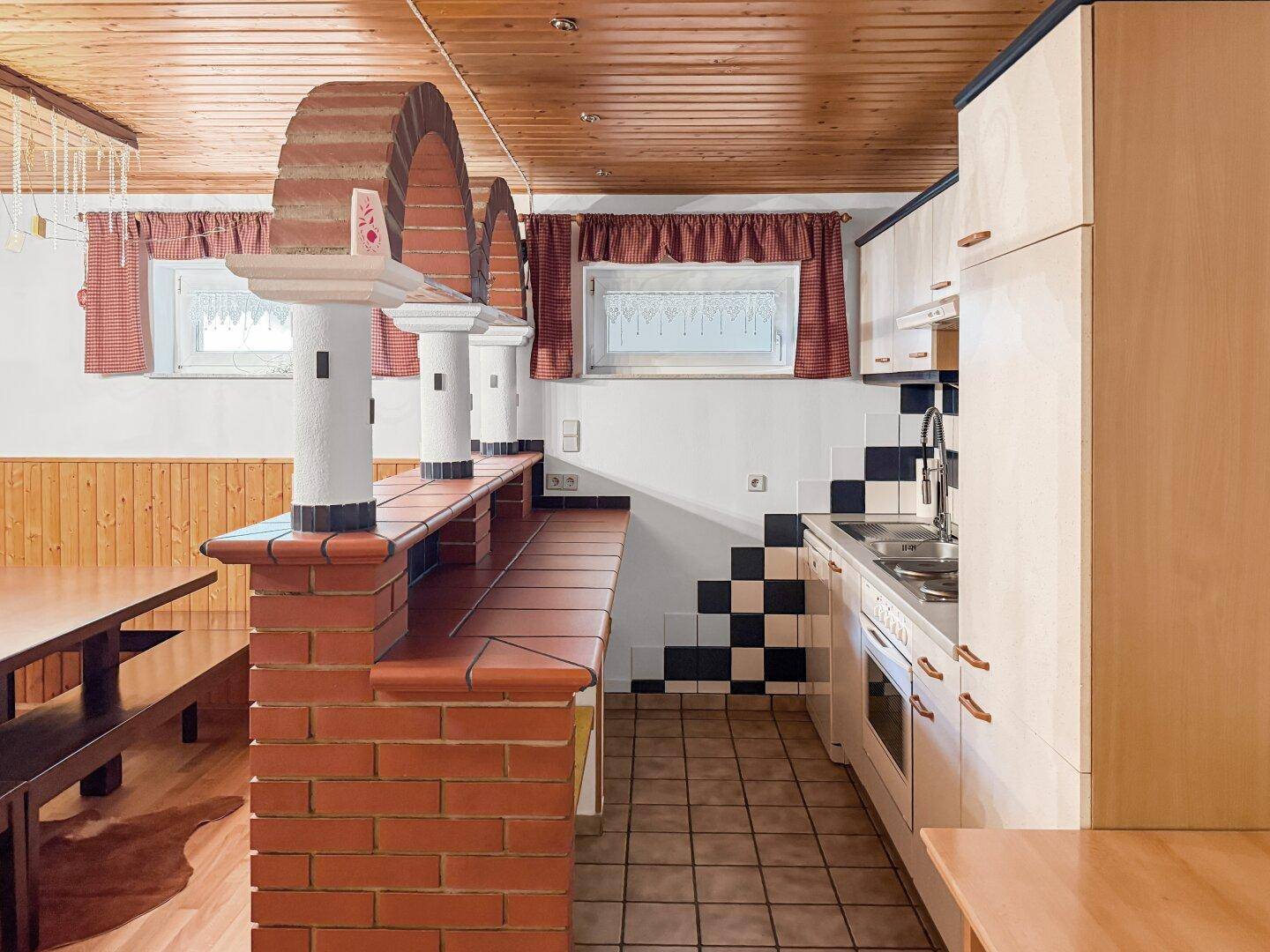 Rustikale Küche mit Ziegeltheke, Holztisch und Holzdecke, ideal für gesellige Runden.