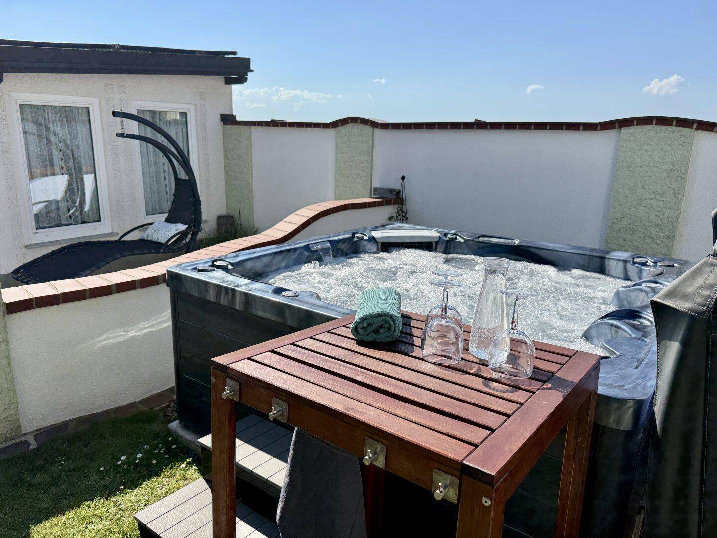 Entspannender Whirlpool im Freien mit sprudelndem Wasser, umgeben von einer kleinen Grünfläche.