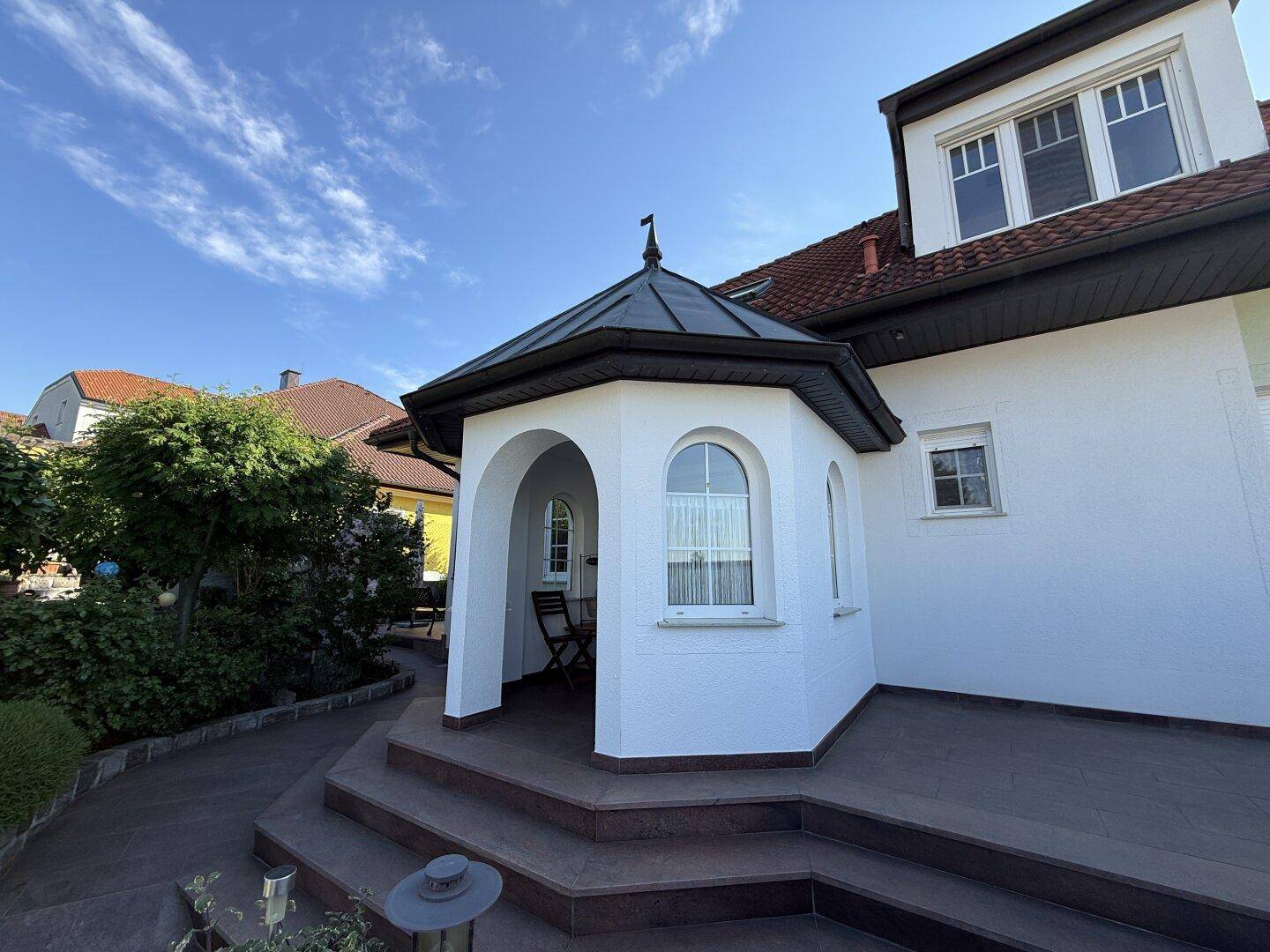 Einladender Hauseingang mit markantem Erker und breiter Treppe.