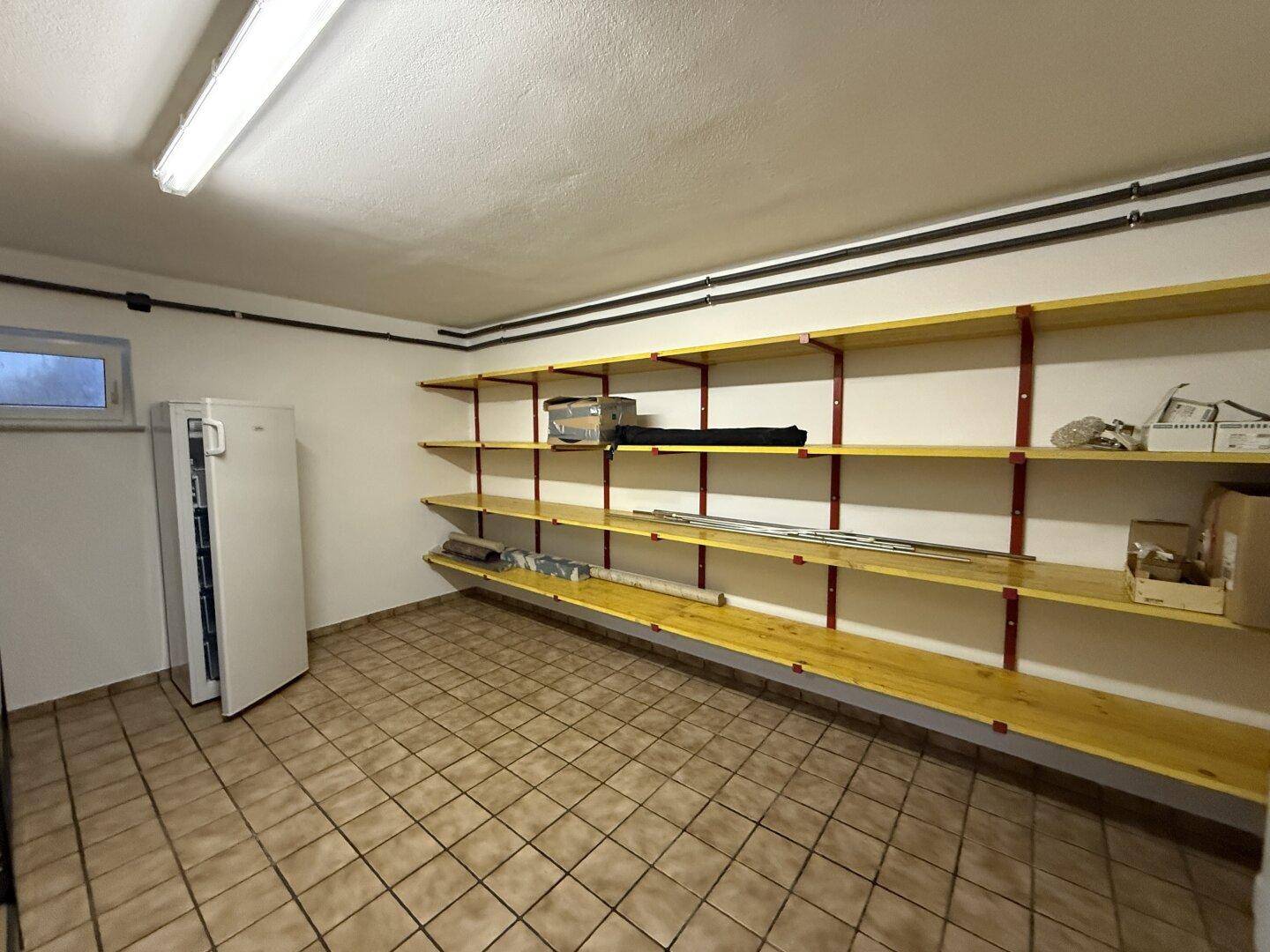 Praktischer Abstellraum mit vielen Regalen und einem Kühlschrank für zusätzlichen Stauraum.