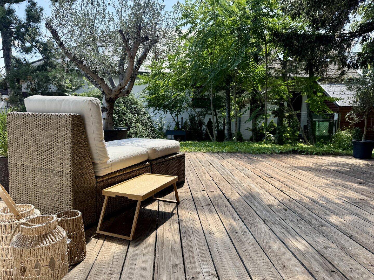 Detailansicht der Holzterrasse mit Liegestuhl und Blick in den Garten.