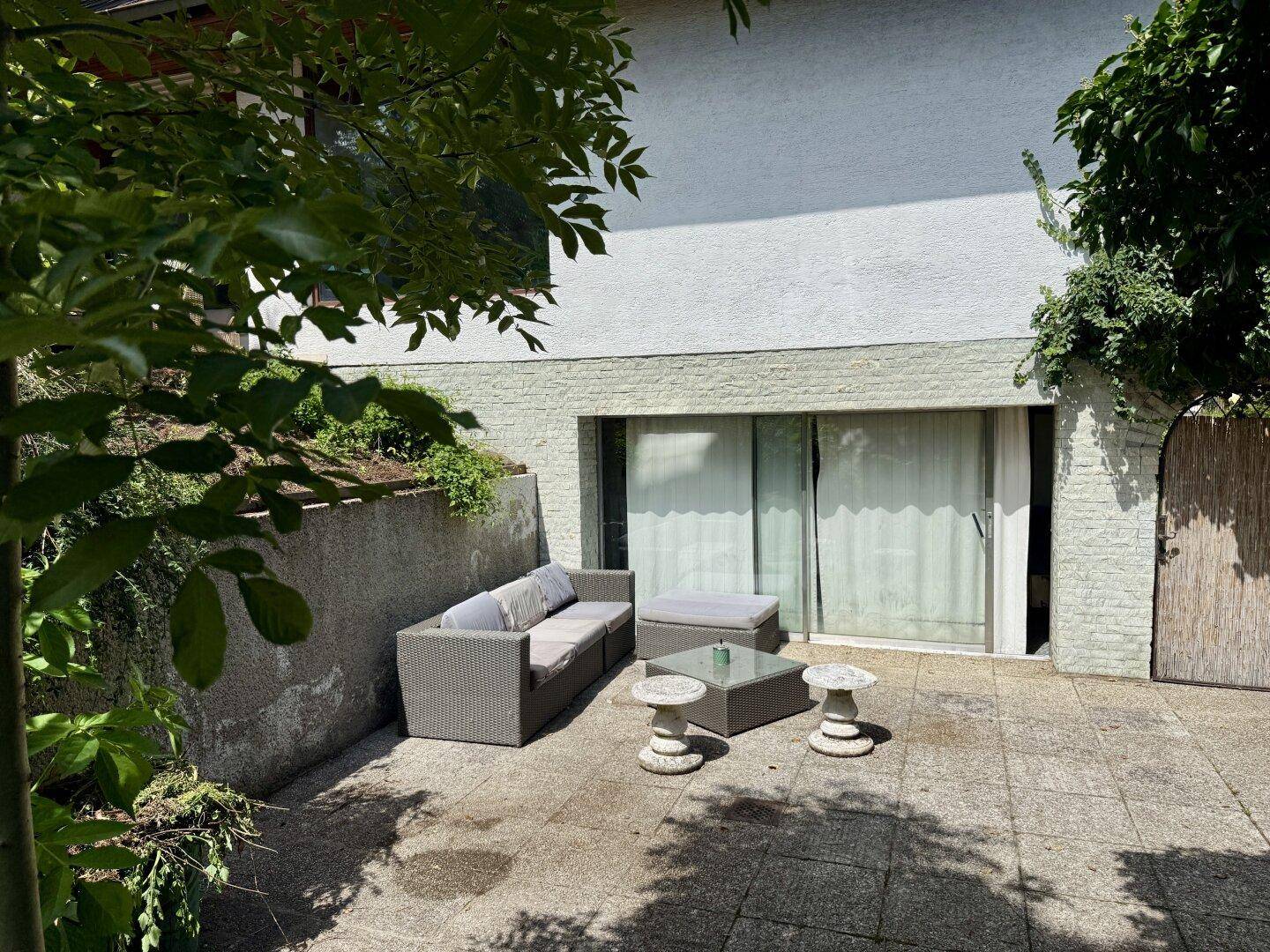Gepflasterte Terrasse mit Outdoor-Möbeln und Zugang zum Haus.