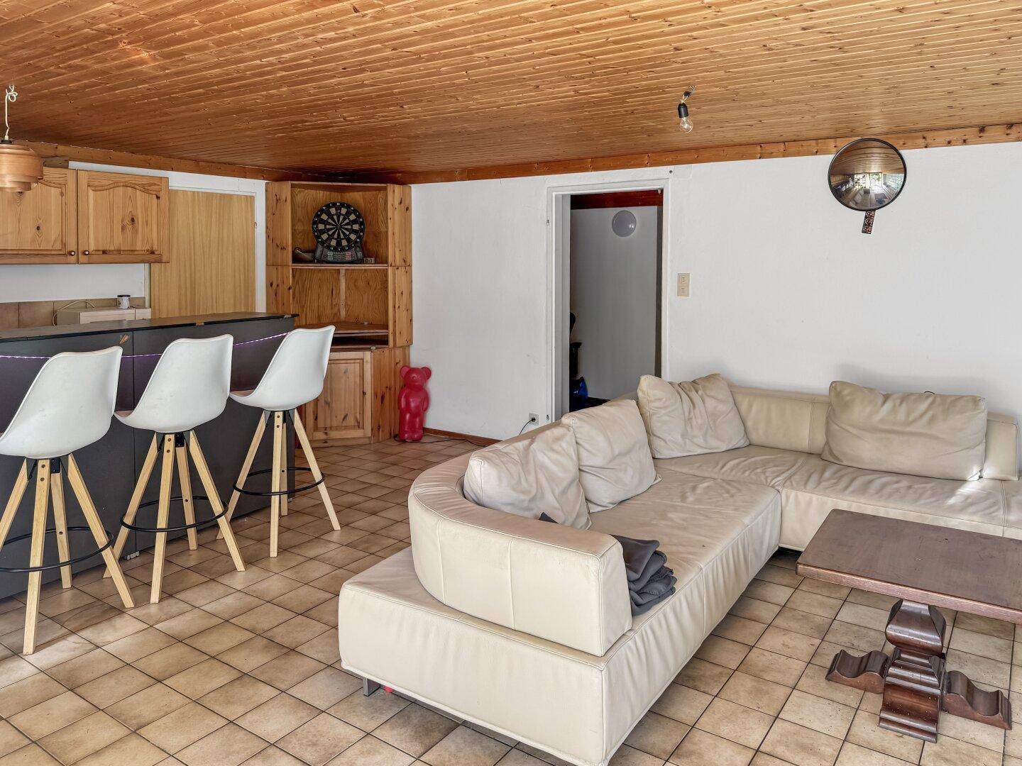 Gemütlicher Hobbyraum im Keller mit Bar, Sofa und Fliesenboden.