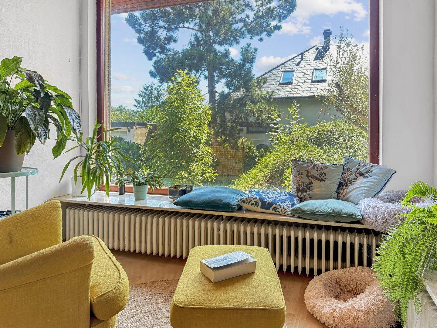 Detailansicht des großen Wohnzimmerfensters mit Blick ins Grüne und gemütlicher Fensterbank.