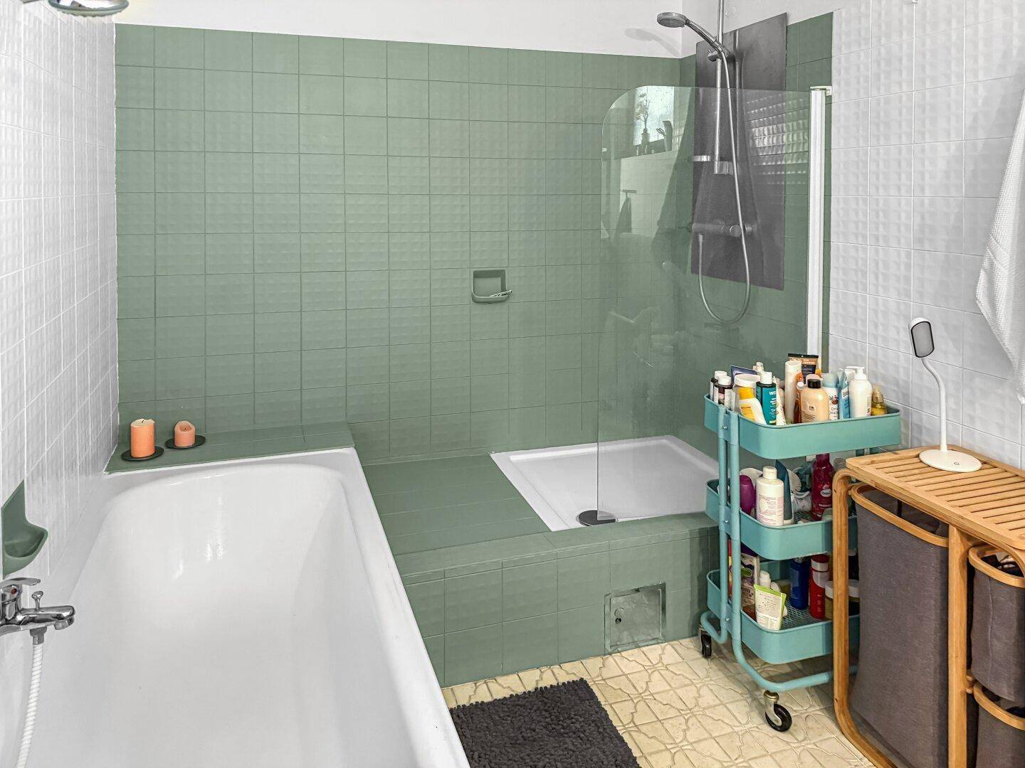 Badezimmer mit Badewanne, Duschbereich und grünen Wandfliesen.