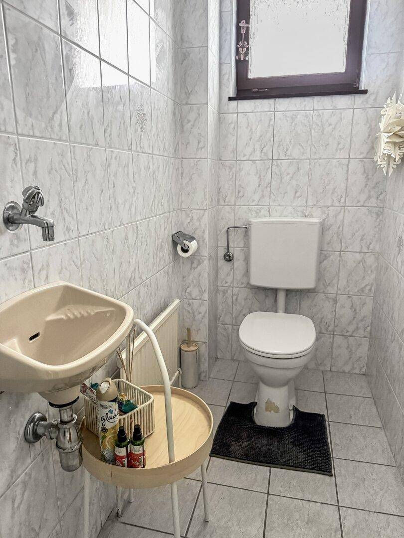Kleines Gäste-WC mit Fenster, WC und Waschbecken.