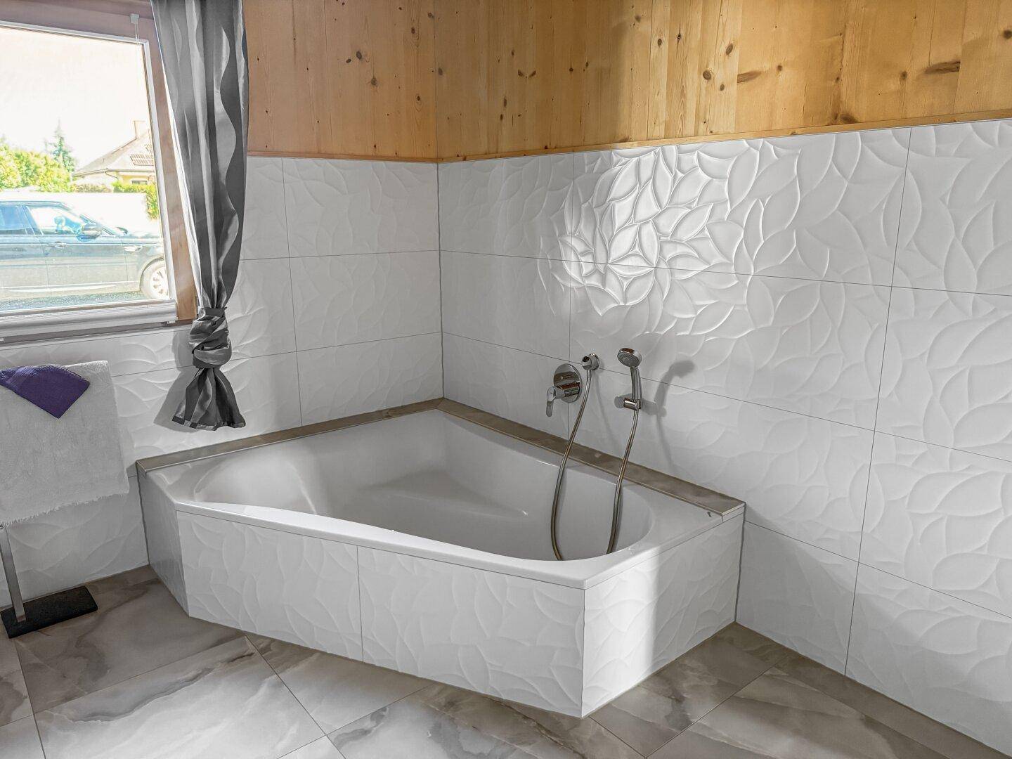 Eckbadewanne in einem modernen Badezimmer mit strukturierten weißen Fliesen und Holzwänden.
