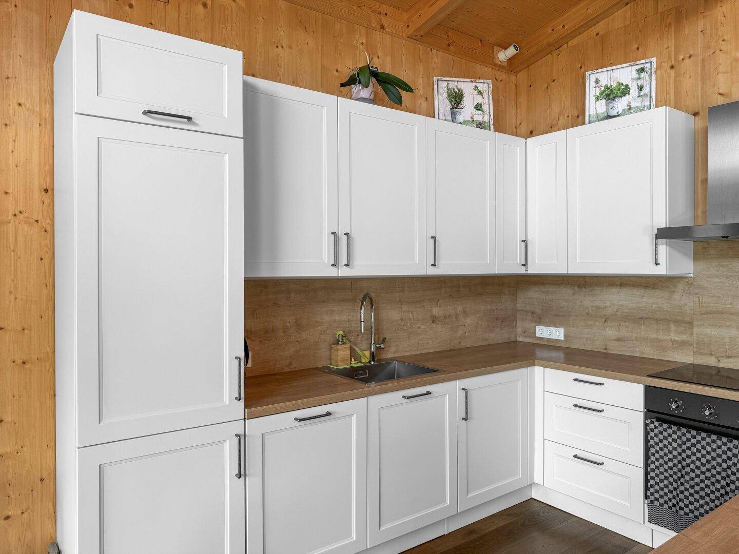 Helle Einbauküche mit weißen Schränken, Holz-Arbeitsplatte und integriertem Spülbecken, funktional und stilvoll.