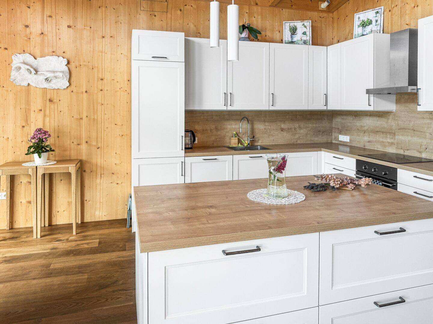Moderne Küche mit weißen Fronten, Holz-Arbeitsplatten und einer zentralen Kücheninsel, die zum Kochen einlädt.