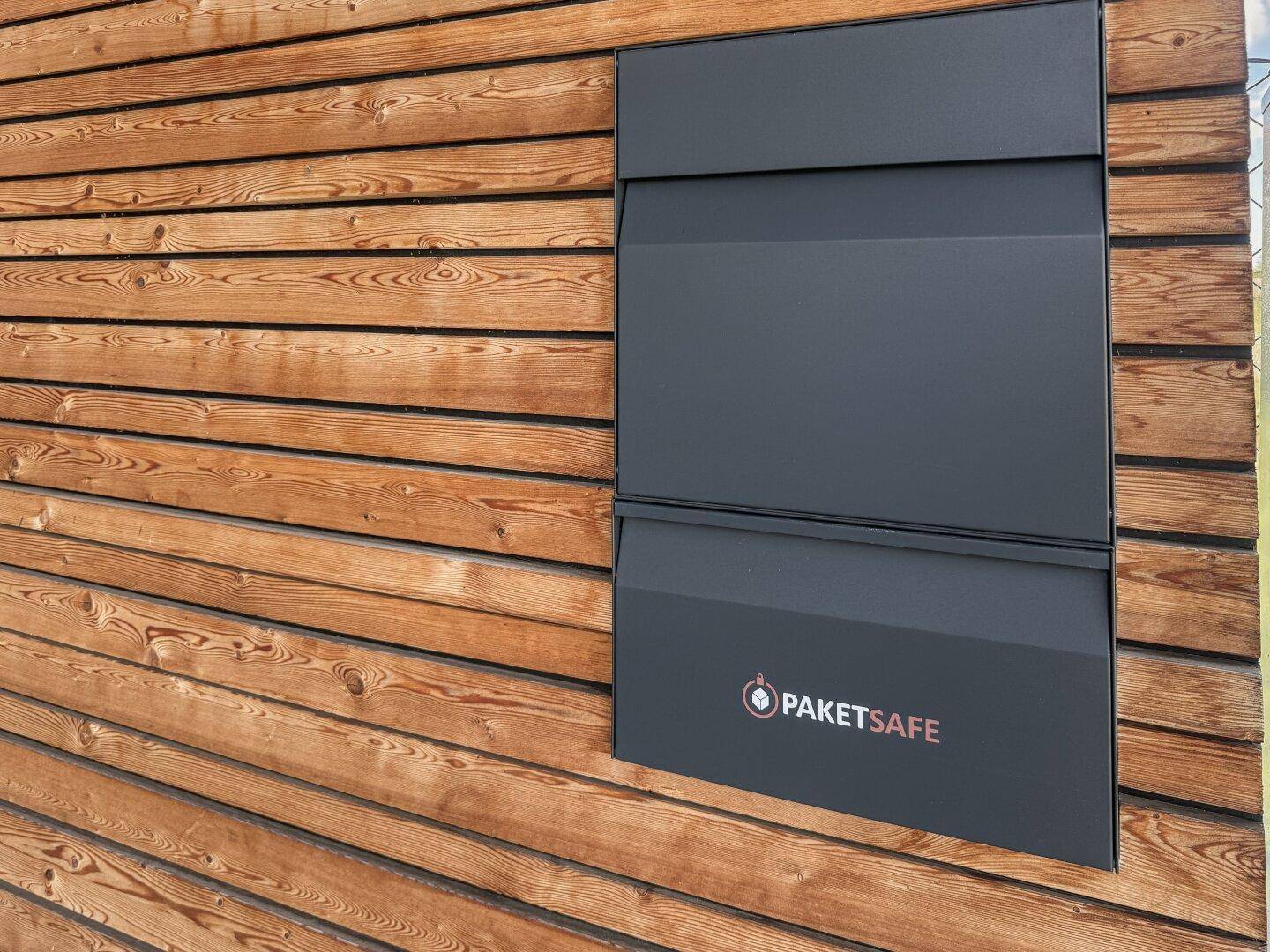 Moderner Paketsafe an der Holzfassade des Hauses für bequeme Lieferungen.