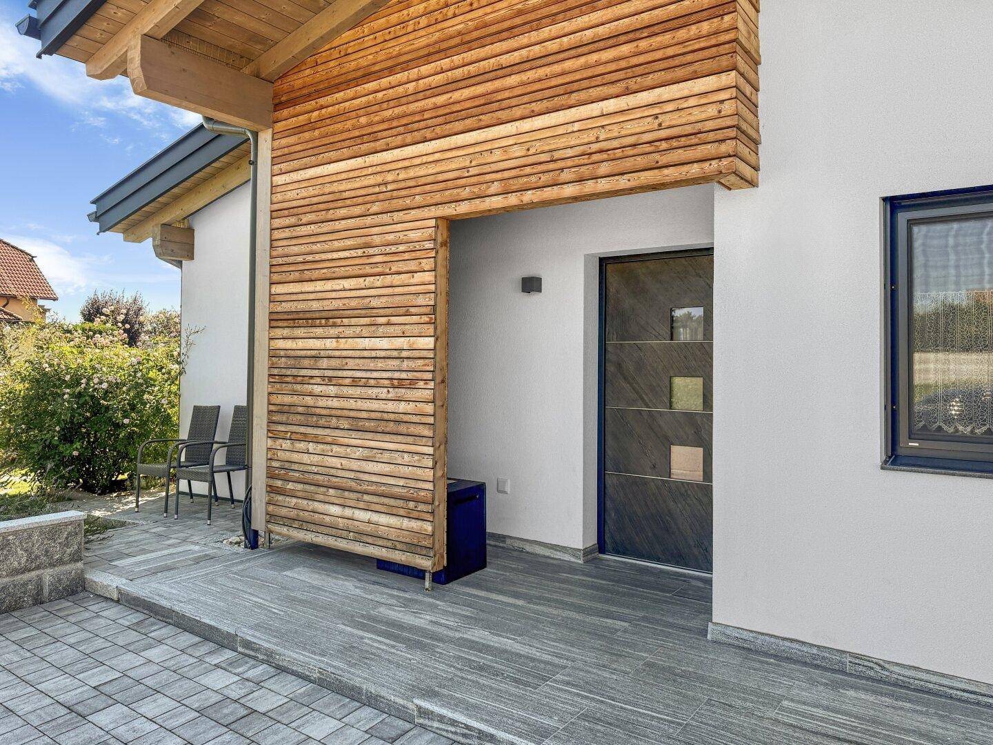 Moderner Eingangsbereich des Hauses mit Holzverkleidung und stilvoller Haustür.