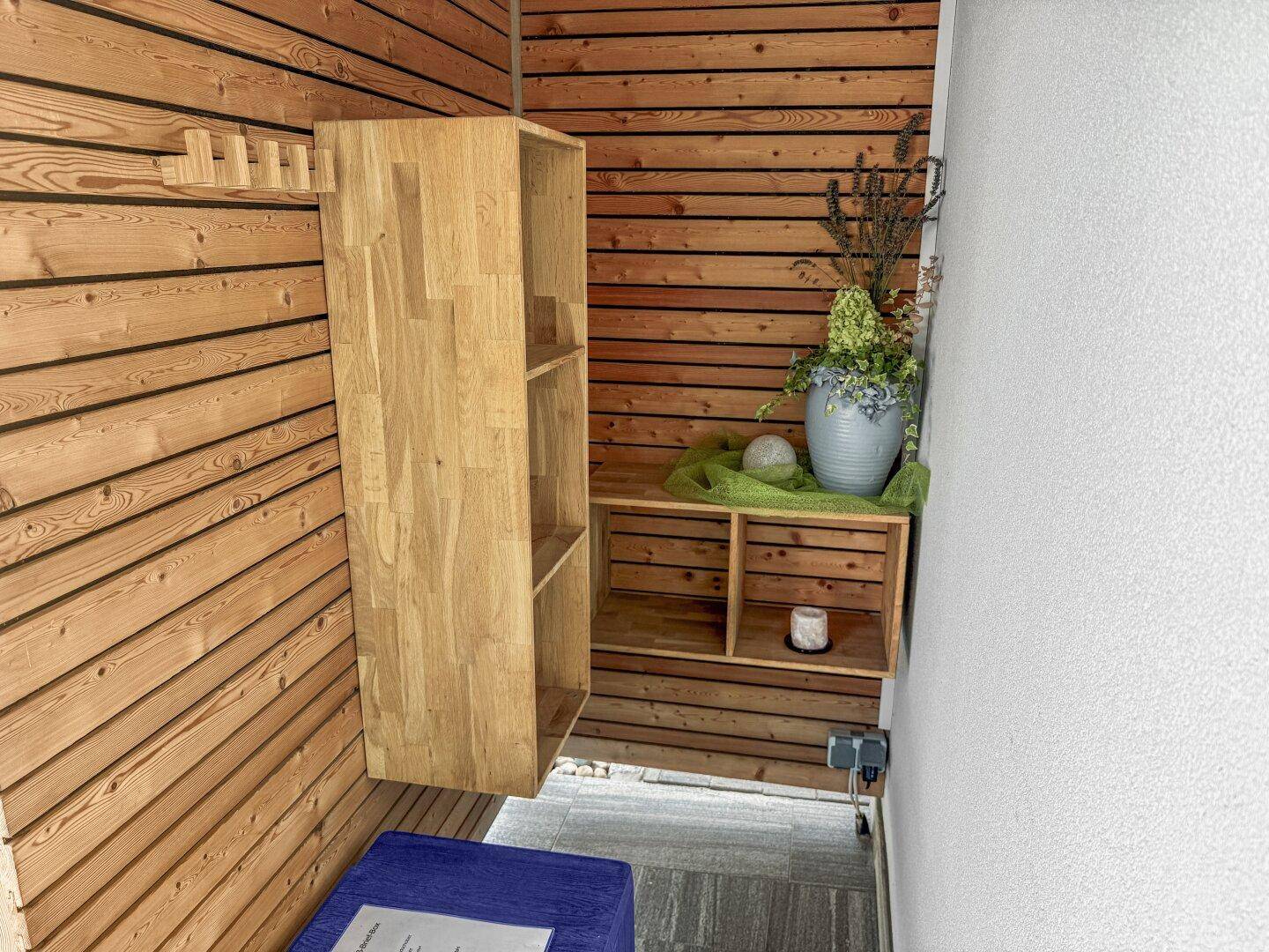 Kleiner Raum mit Holzwänden und Regalen, ideal als Garderobe oder Abstellraum.