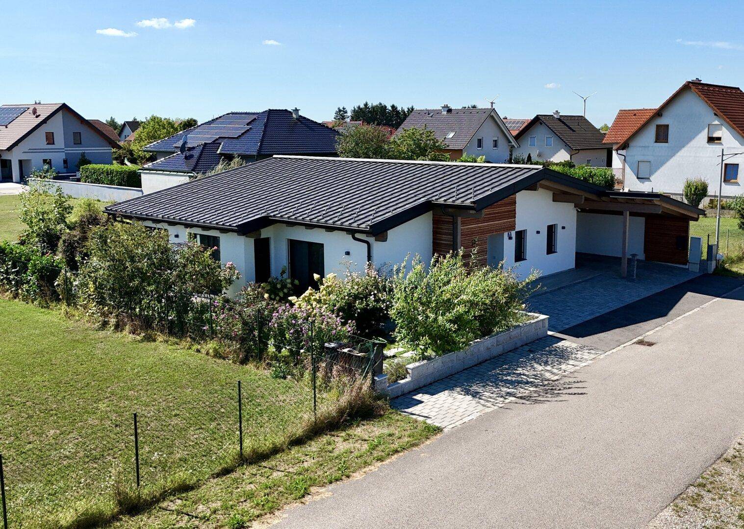Vogelperspektive des modernen Hauses mit Garten, Carport und der ruhigen Wohngegend.