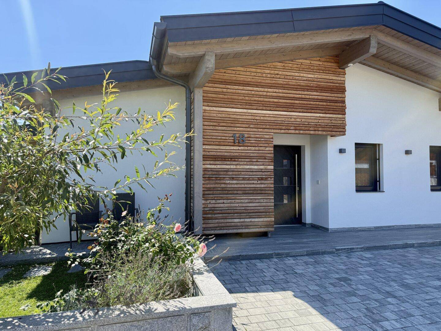 Vorderansicht des modernen Hauses mit gepflasterter Auffahrt und gepflegtem Vorgarten.