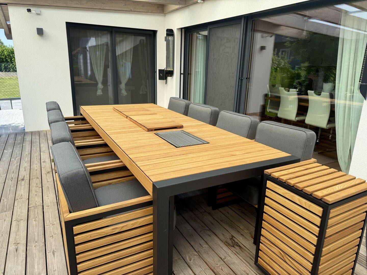 Moderner Esstisch aus Holz und Metall auf der Terrasse mit integriertem Grillbereich.