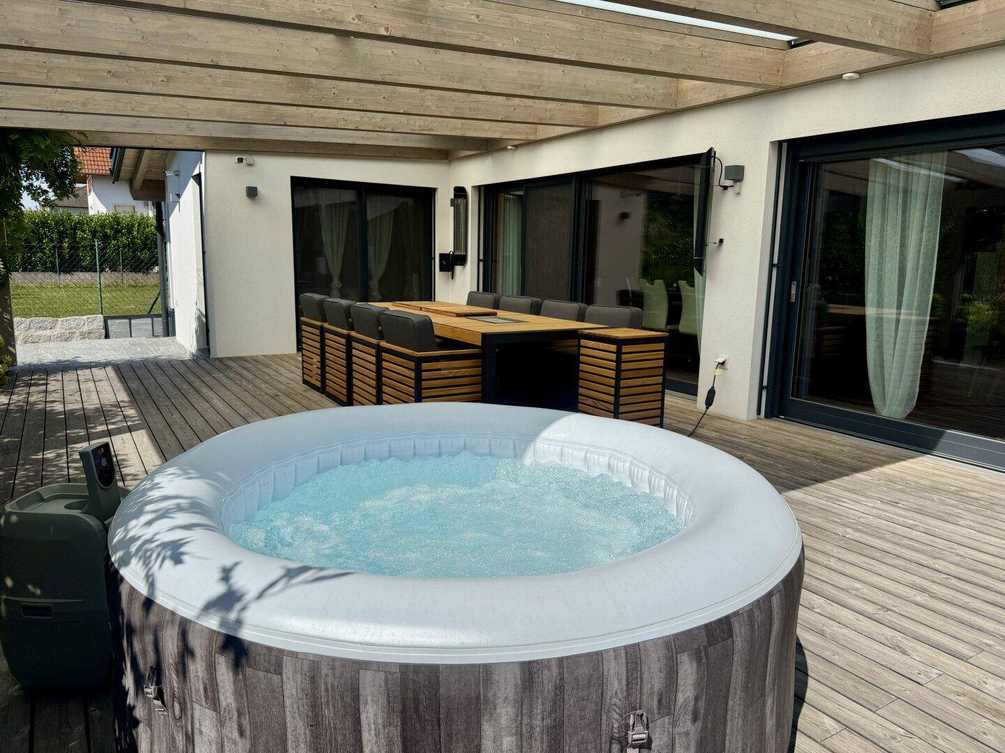 Aufblasbarer Whirlpool auf der Holzterrasse, umgeben von einem modernen Essbereich.