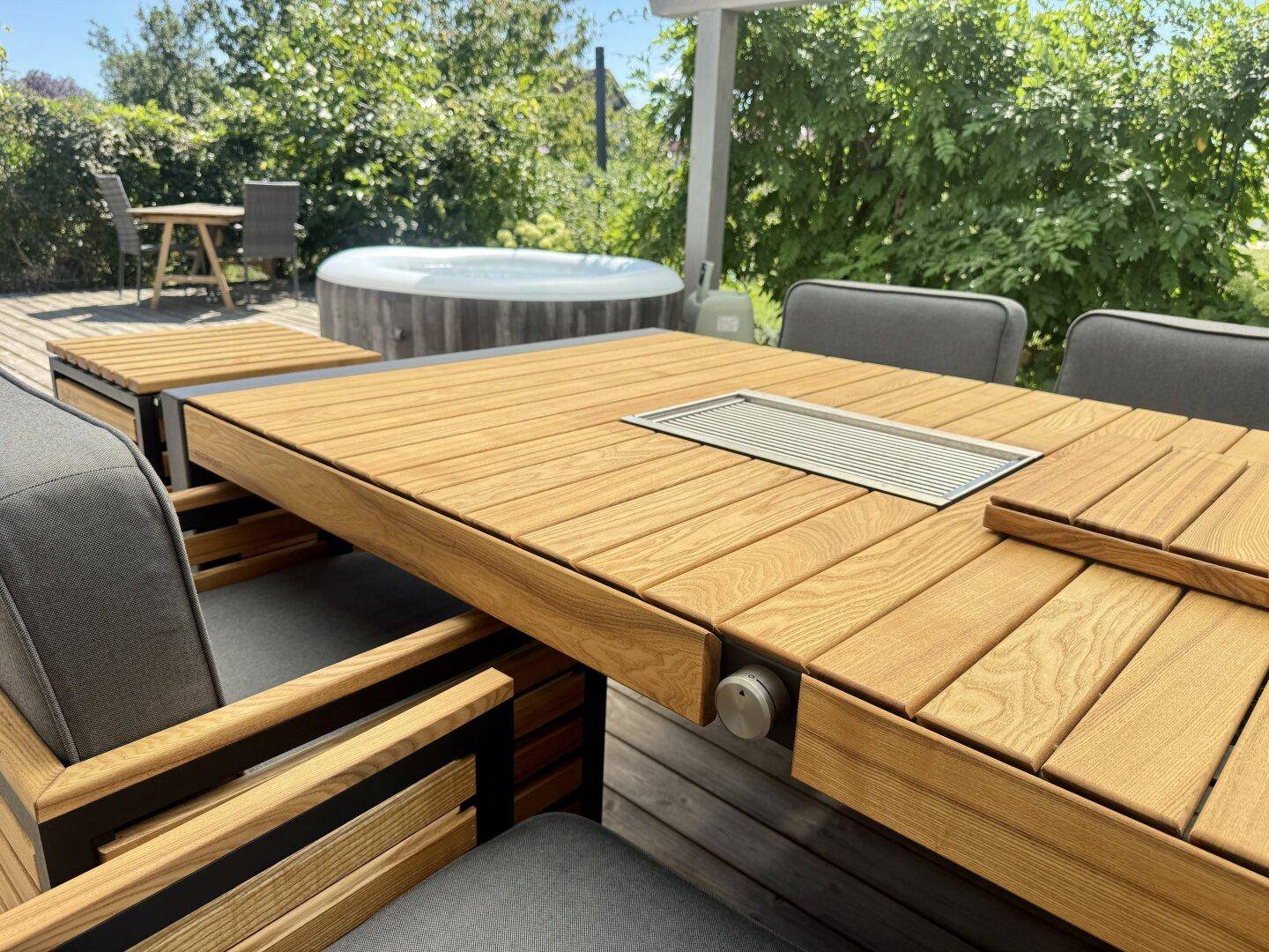Detailansicht des modernen Esstisches auf der Holzterrasse mit integriertem Grill.