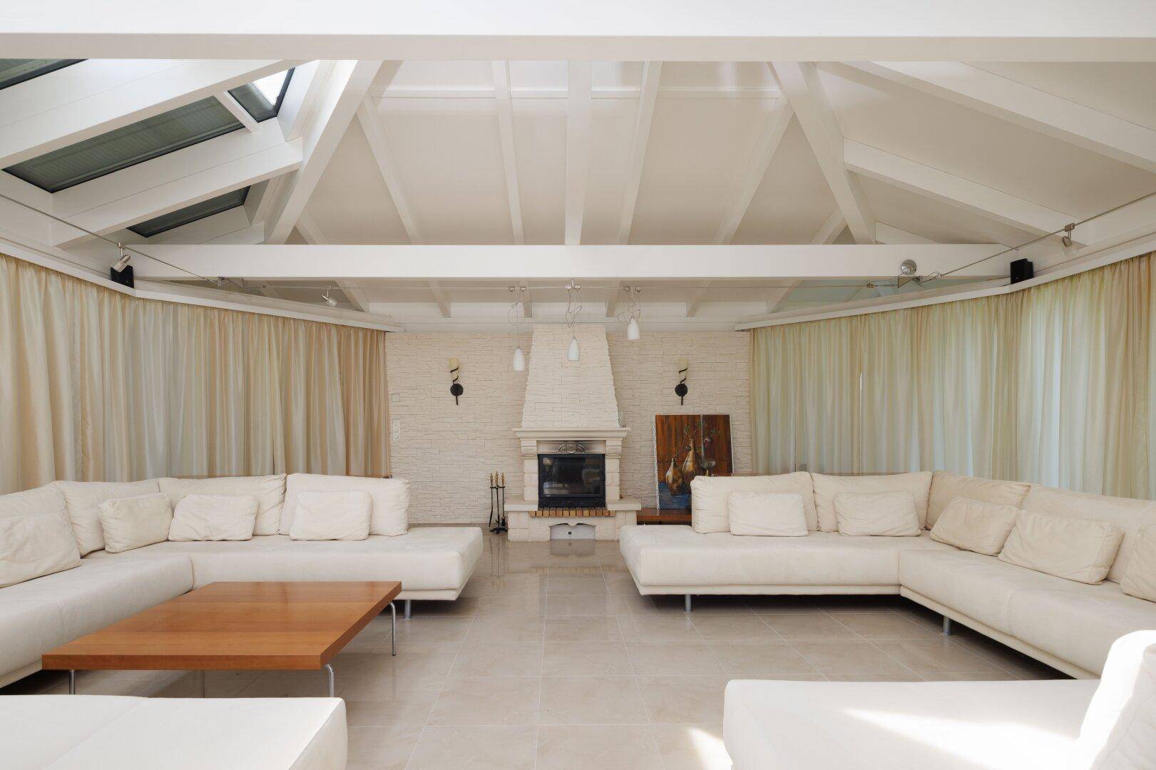 Geräumiges Wohnzimmer mit Kamin, großen Sofas und hohen Decken.
