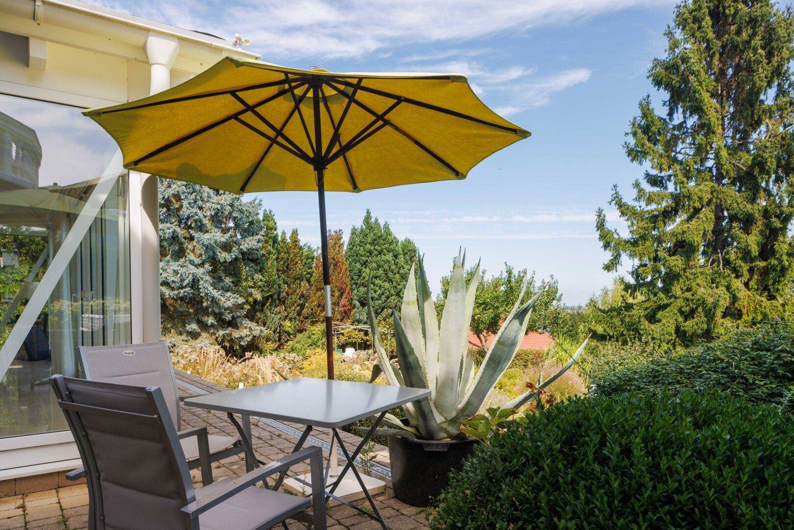 Kleine Terrasse mit Tisch, Stühlen und Blick in die grüne Umgebung.
