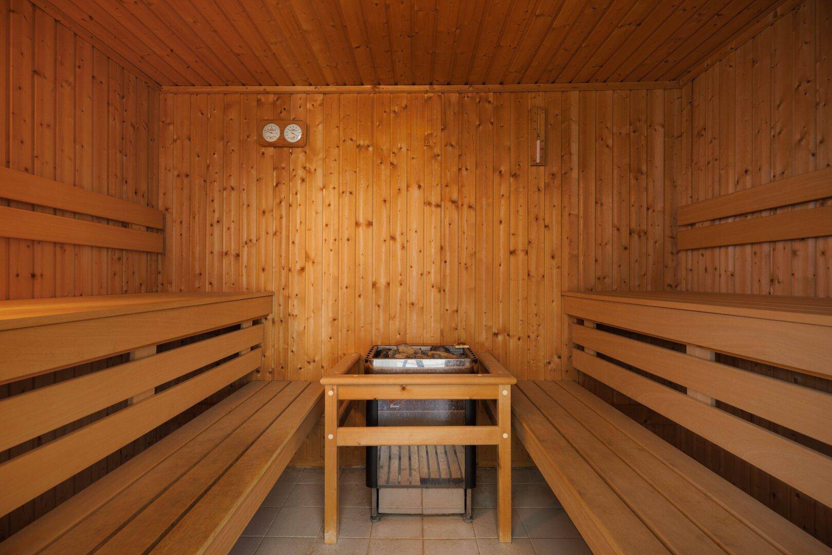 Traditionelle Holzsauna mit Bänken und Heizofen für entspannende Momente.