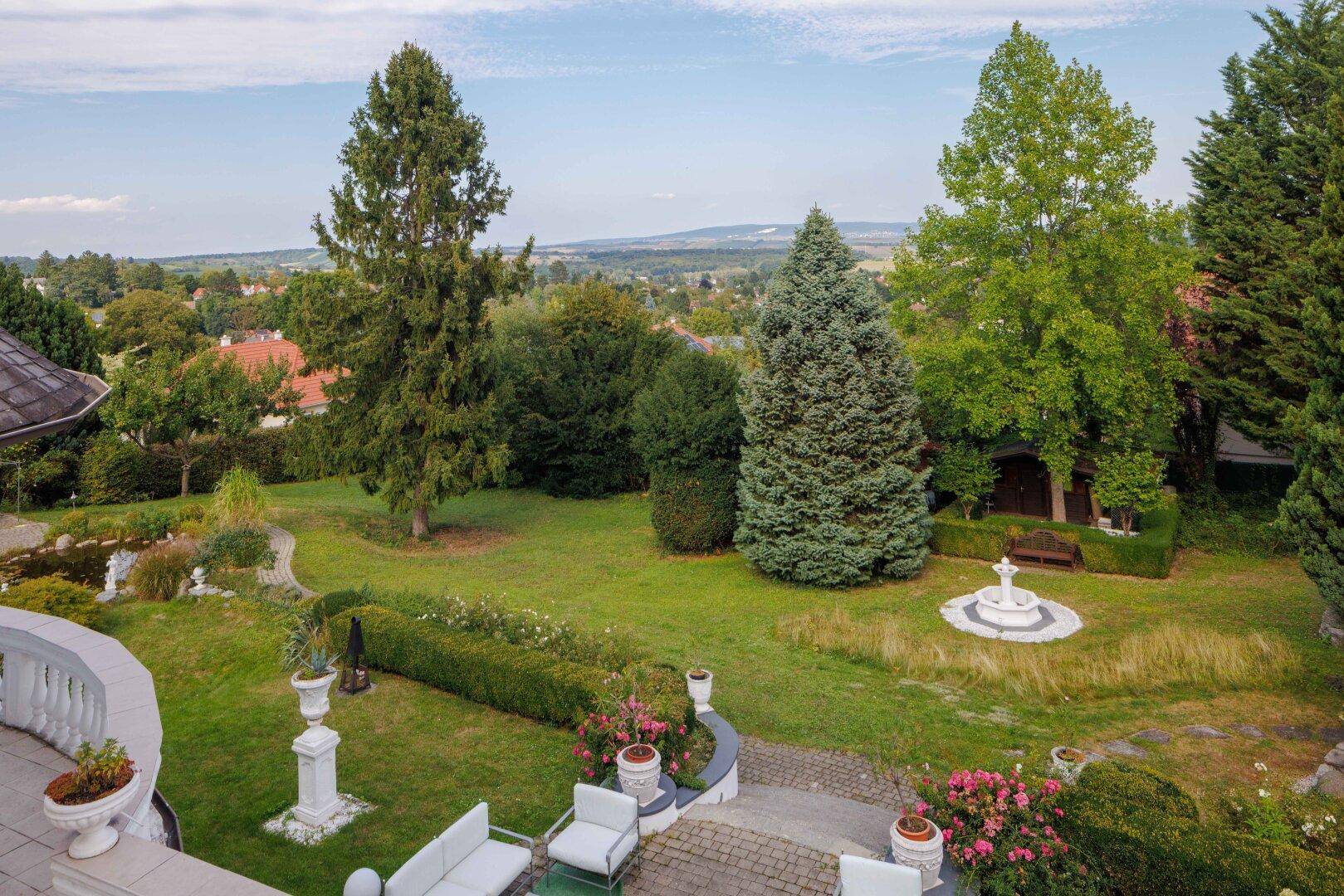 Gepflegter Gartenbereich mit Zierbrunnen, Sitzgelegenheiten und weitem Blick in die Landschaft.