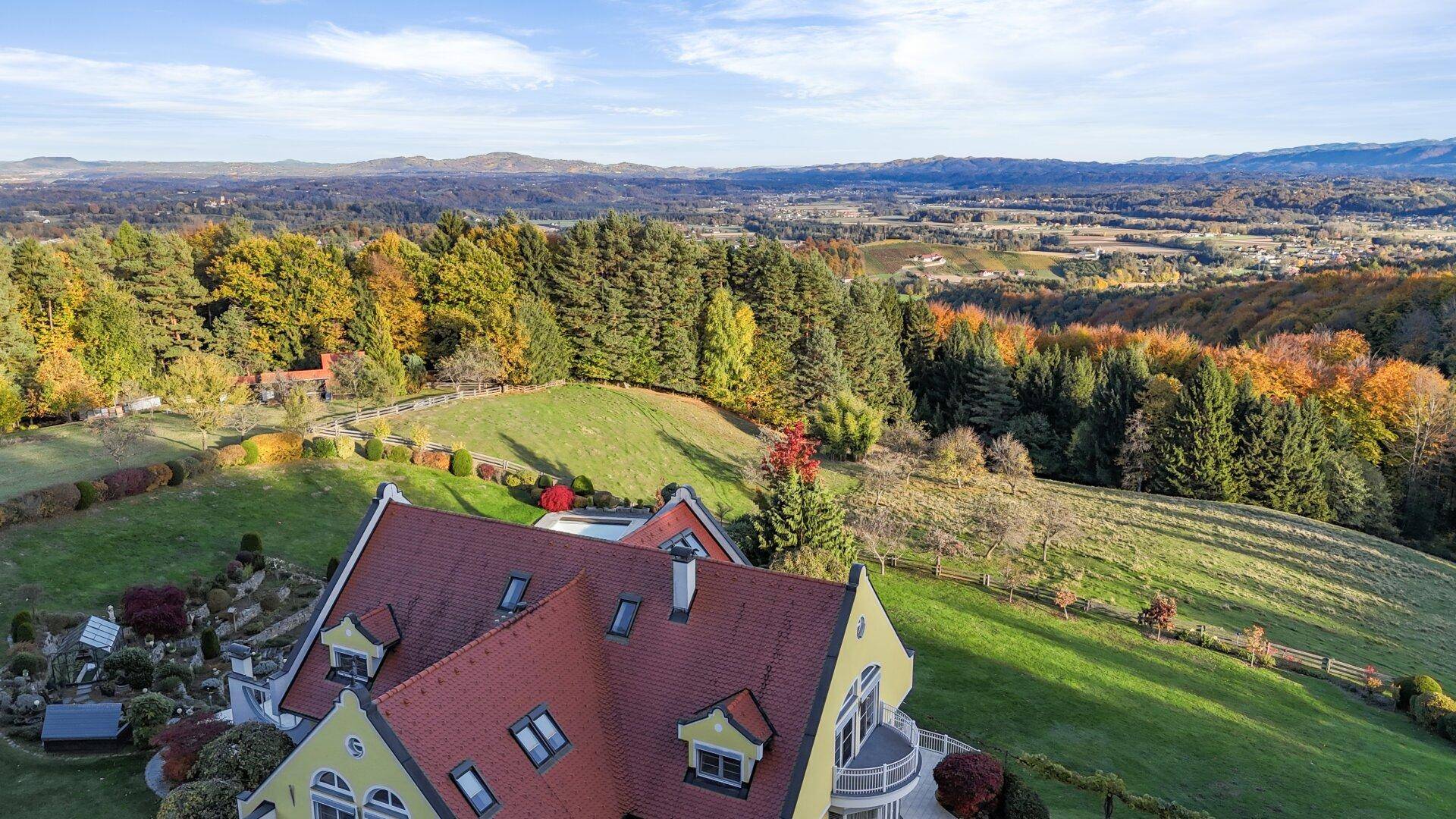 Luftaufnahme der Villa und der umliegenden Landschaft mit Wäldern und Hügeln.