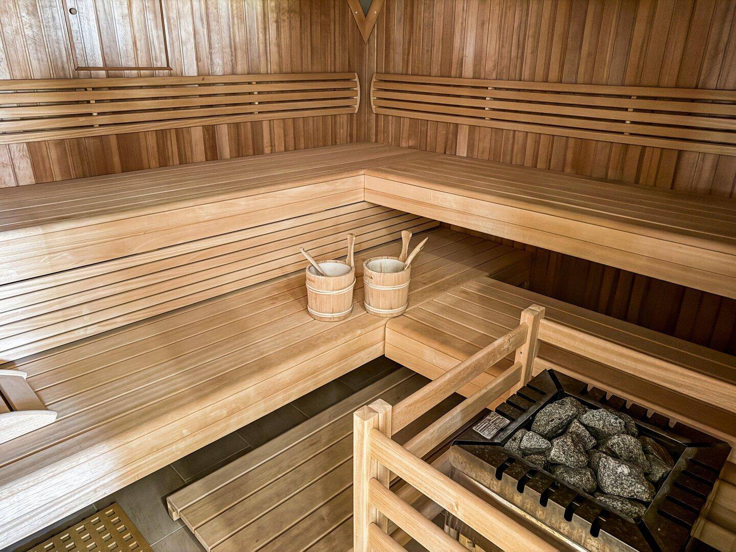 Traditionelle Holzsauna mit Bänken und Saunaofen für entspannende Momente.