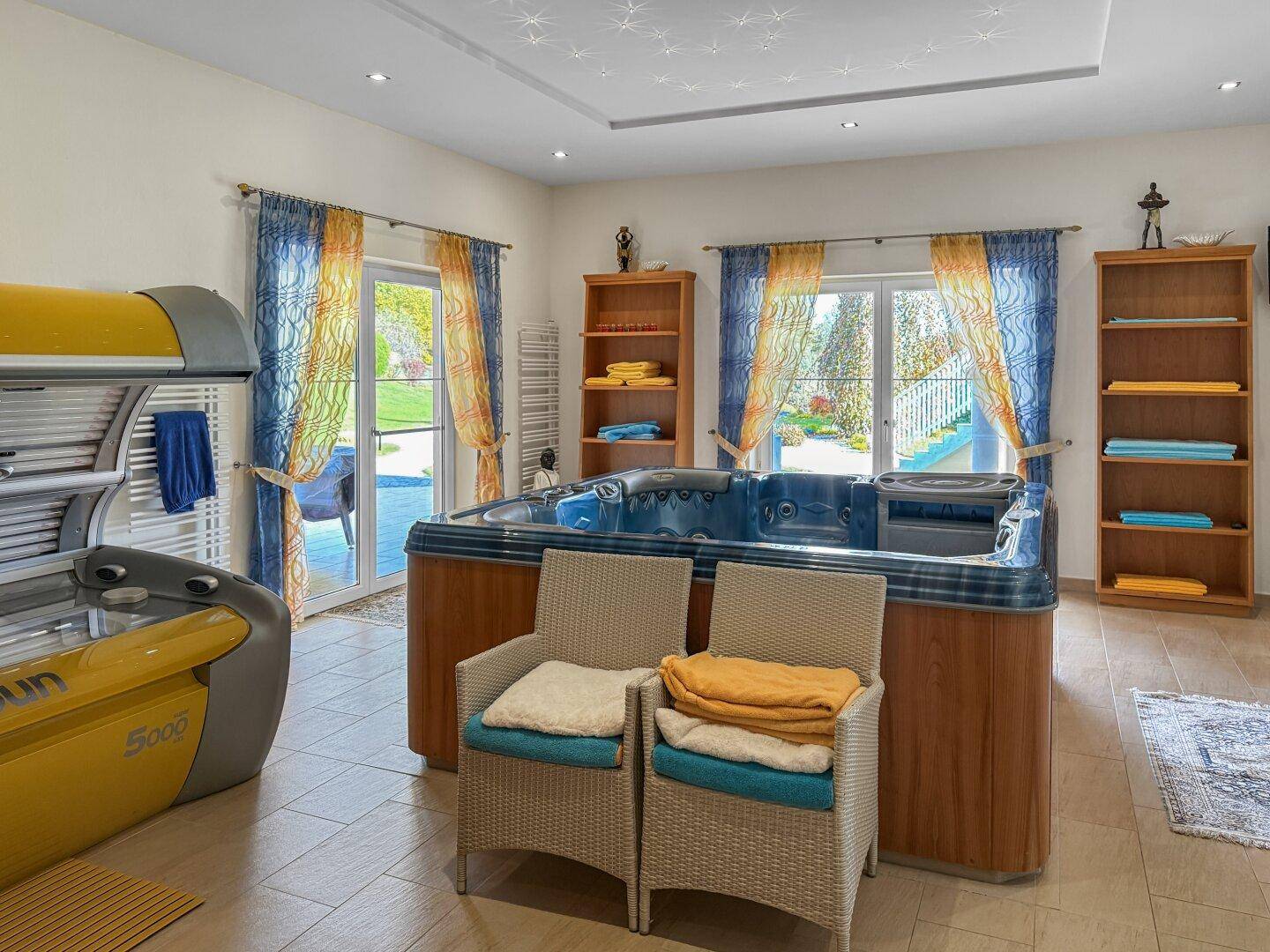 Heller Wellnessraum mit Whirlpool, Solarium und Zugang nach draußen.