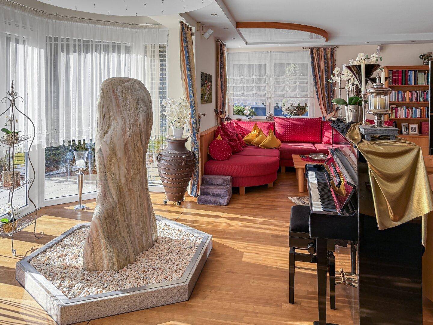 Geräumiges Wohnzimmer mit Holzboden, Klavier und Zugang zum Wintergarten.