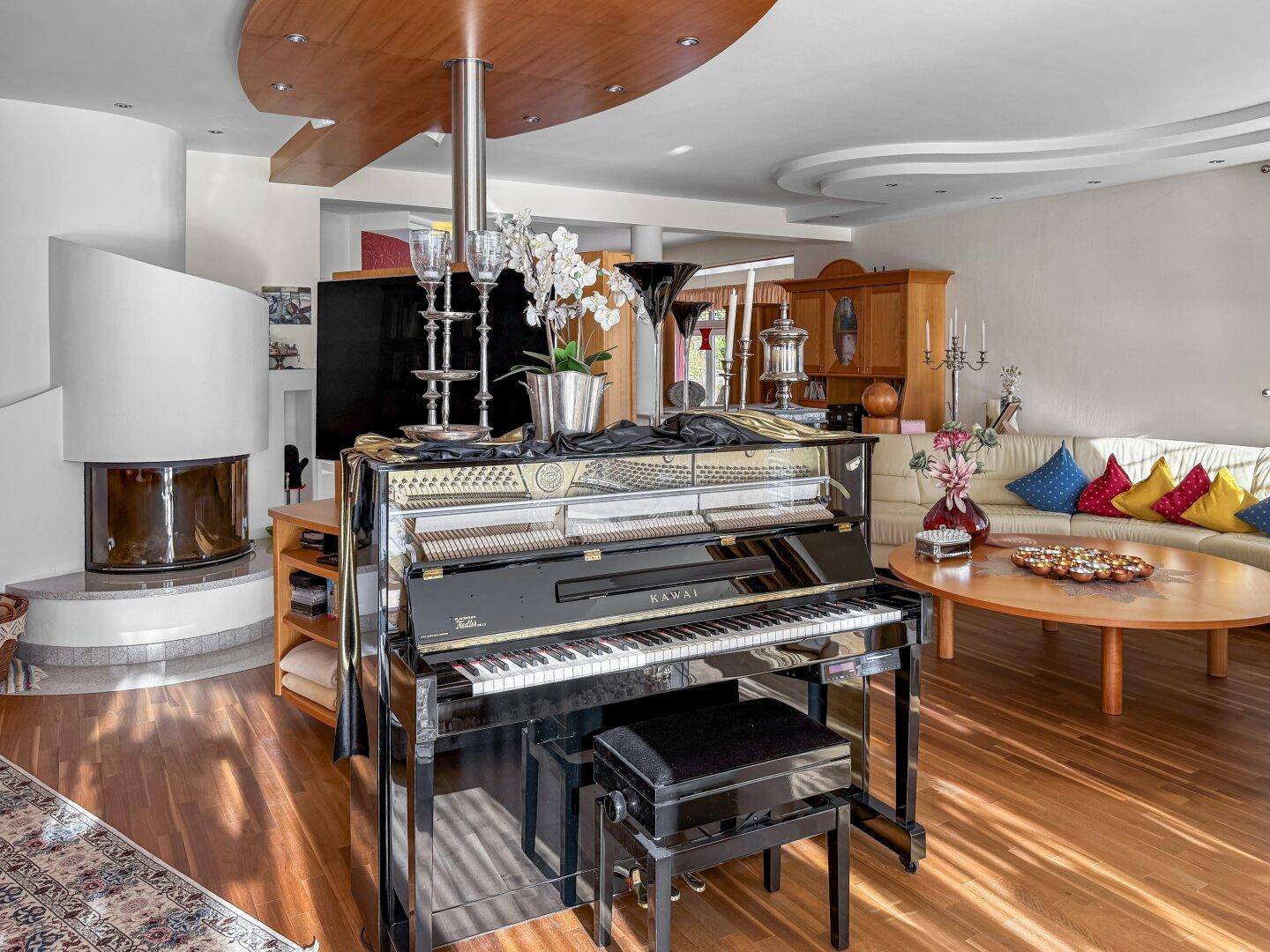 Gemütliches Wohnzimmer mit Klavier, Kamin und bequemer Sitzgruppe.