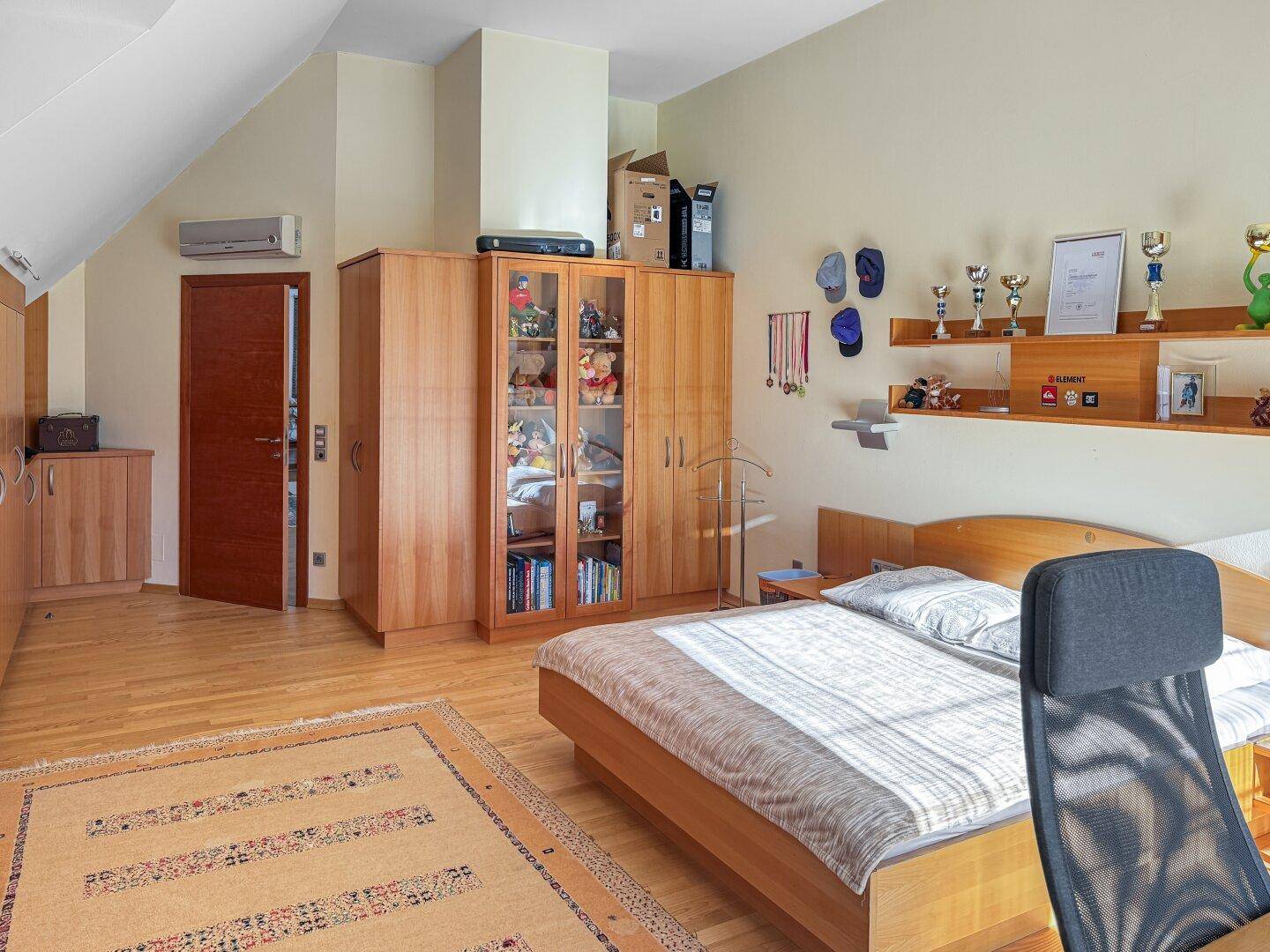 Schlafzimmer mit Holzbett, Kleiderschrank und Klimaanlage.