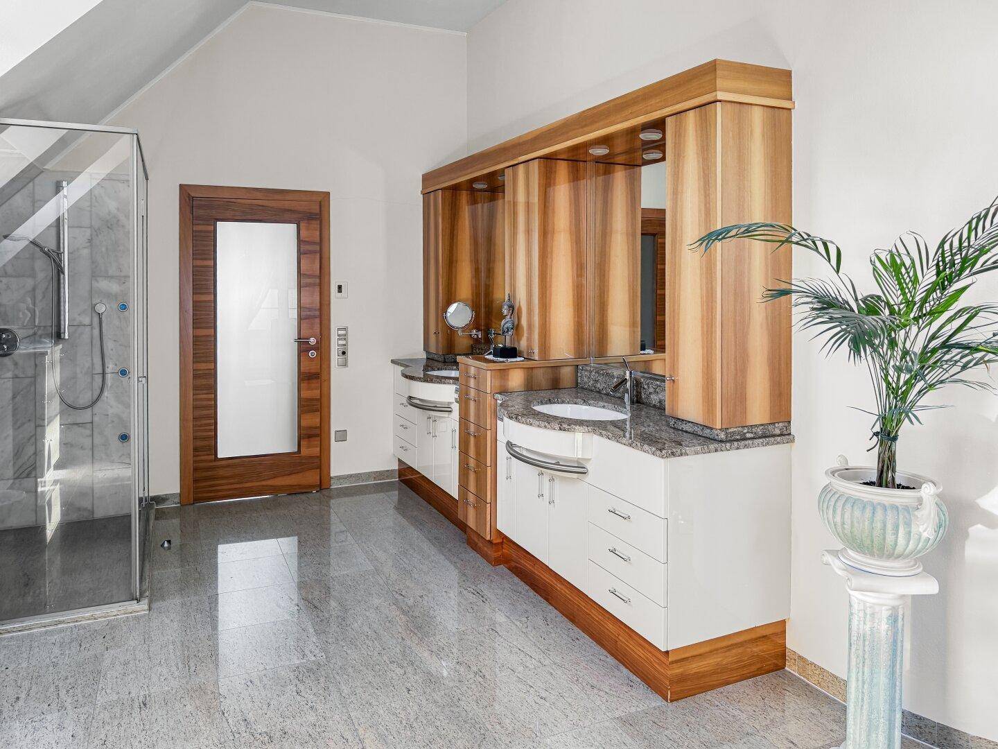 Modernes Badezimmer mit Doppelwaschbecken, Glasdusche und Holzelementen.