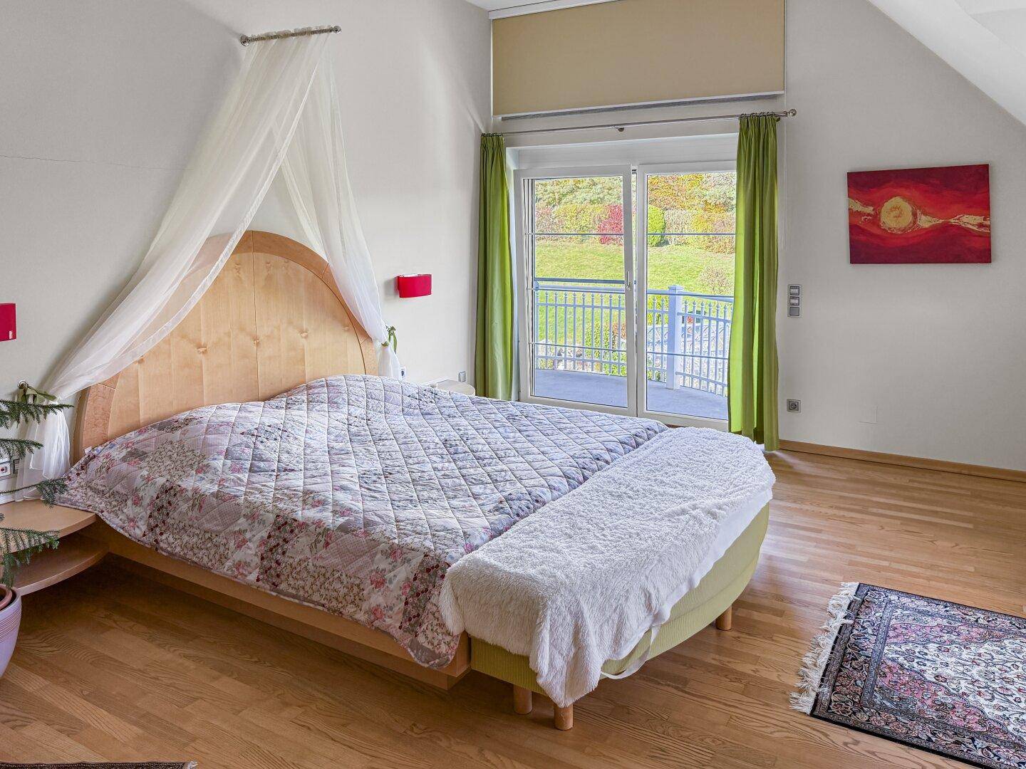 Schlafzimmer mit Himmelbett und direktem Zugang zum Balkon.