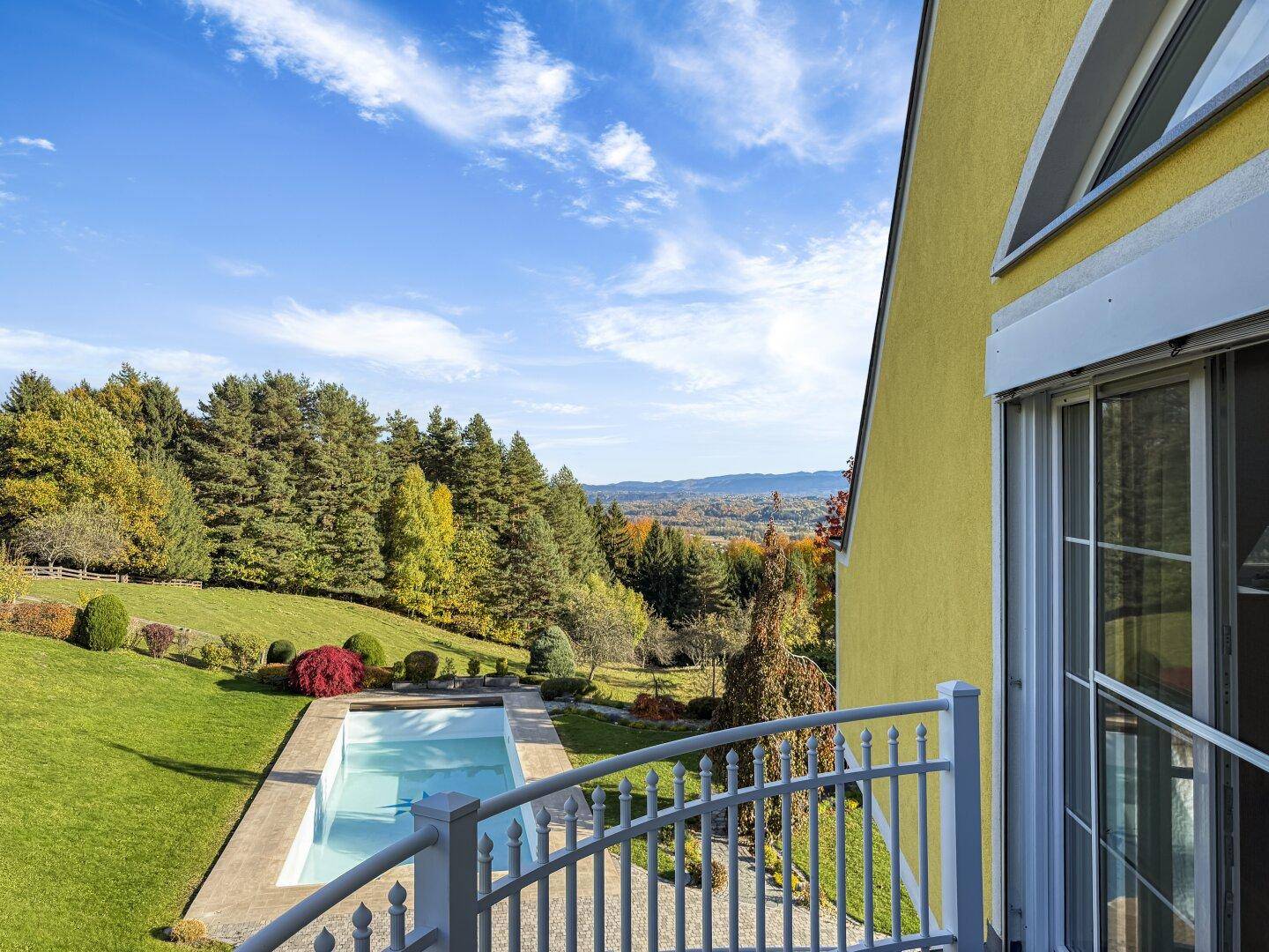 Balkon mit Blick auf den Pool und die umliegende grüne Landschaft.
