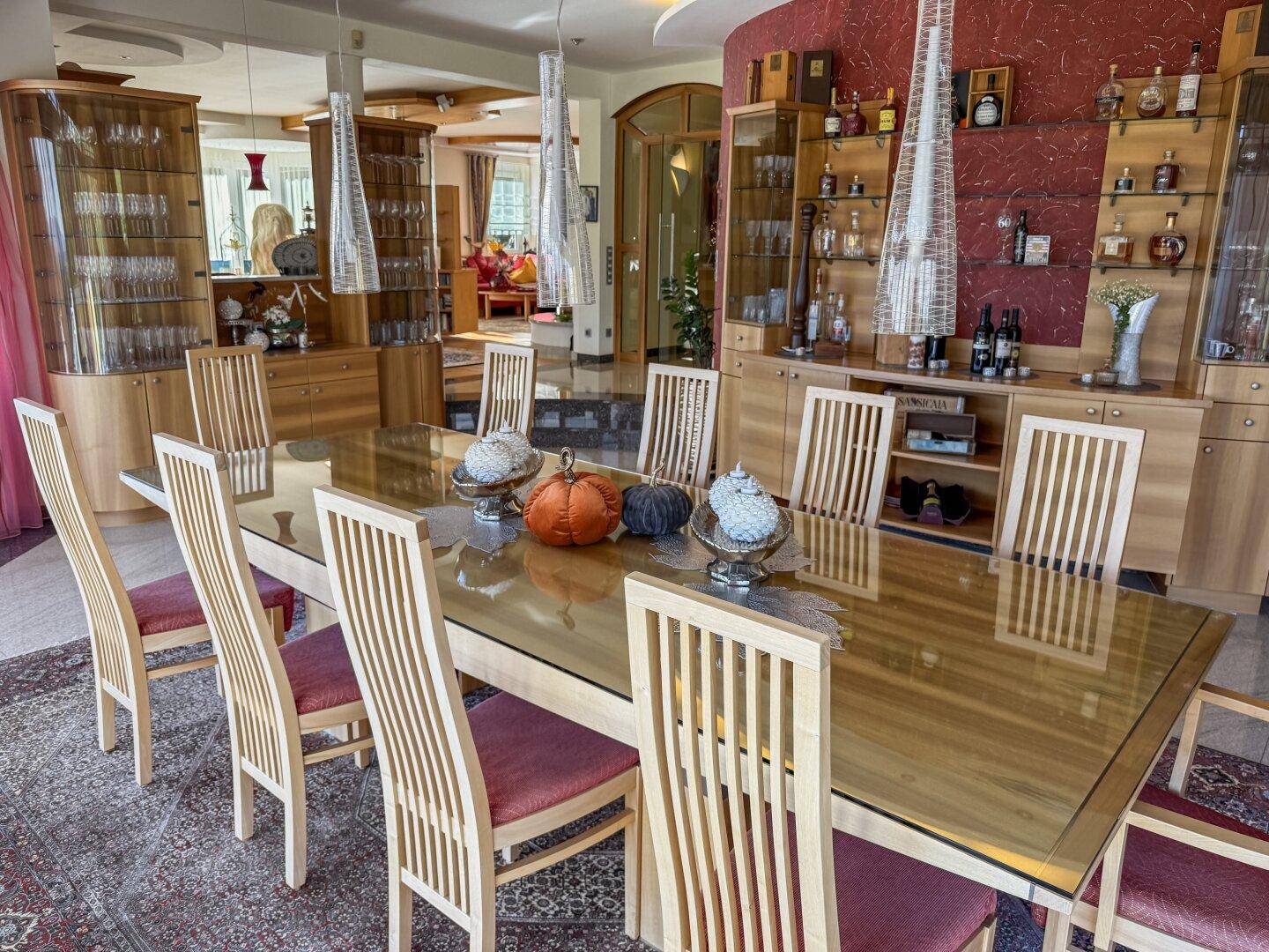 Elegantes Esszimmer mit großem Tisch, Vitrinen und stilvoller Dekoration.