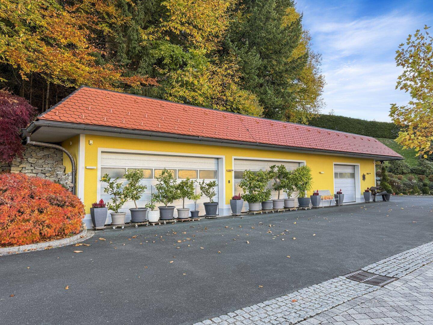 Langes Garagengebäude mit mehreren Toren, gelber Fassade und rotem Dach.