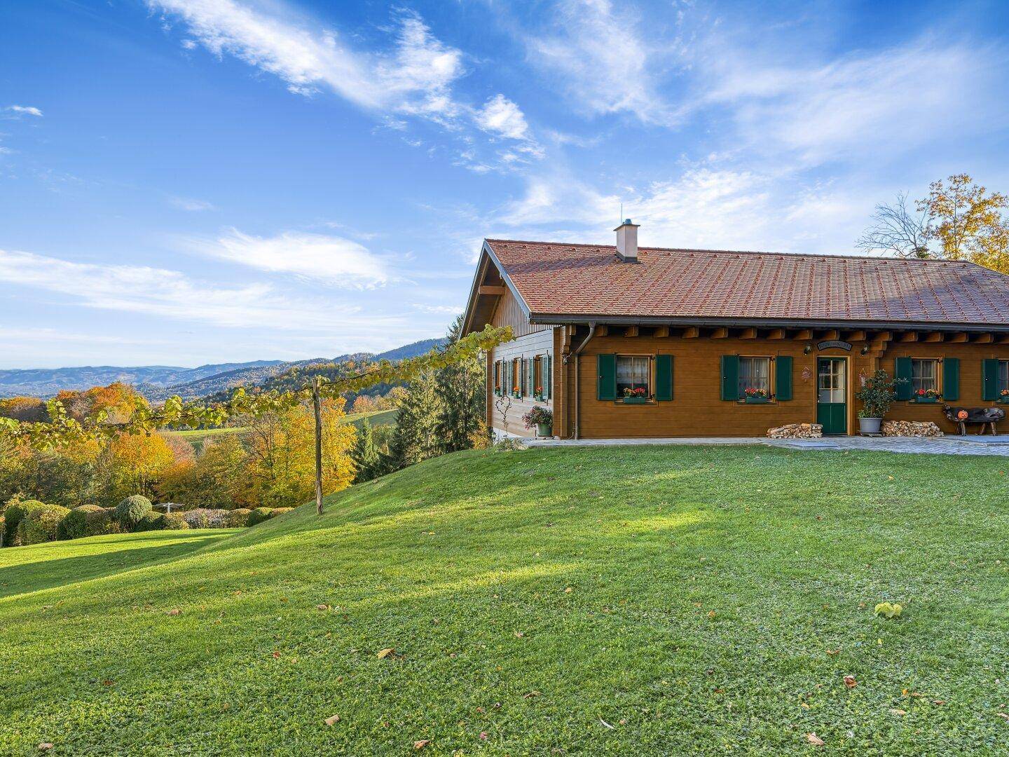 Holzchalet aus der Ferne, eingebettet in die grüne Landschaft.