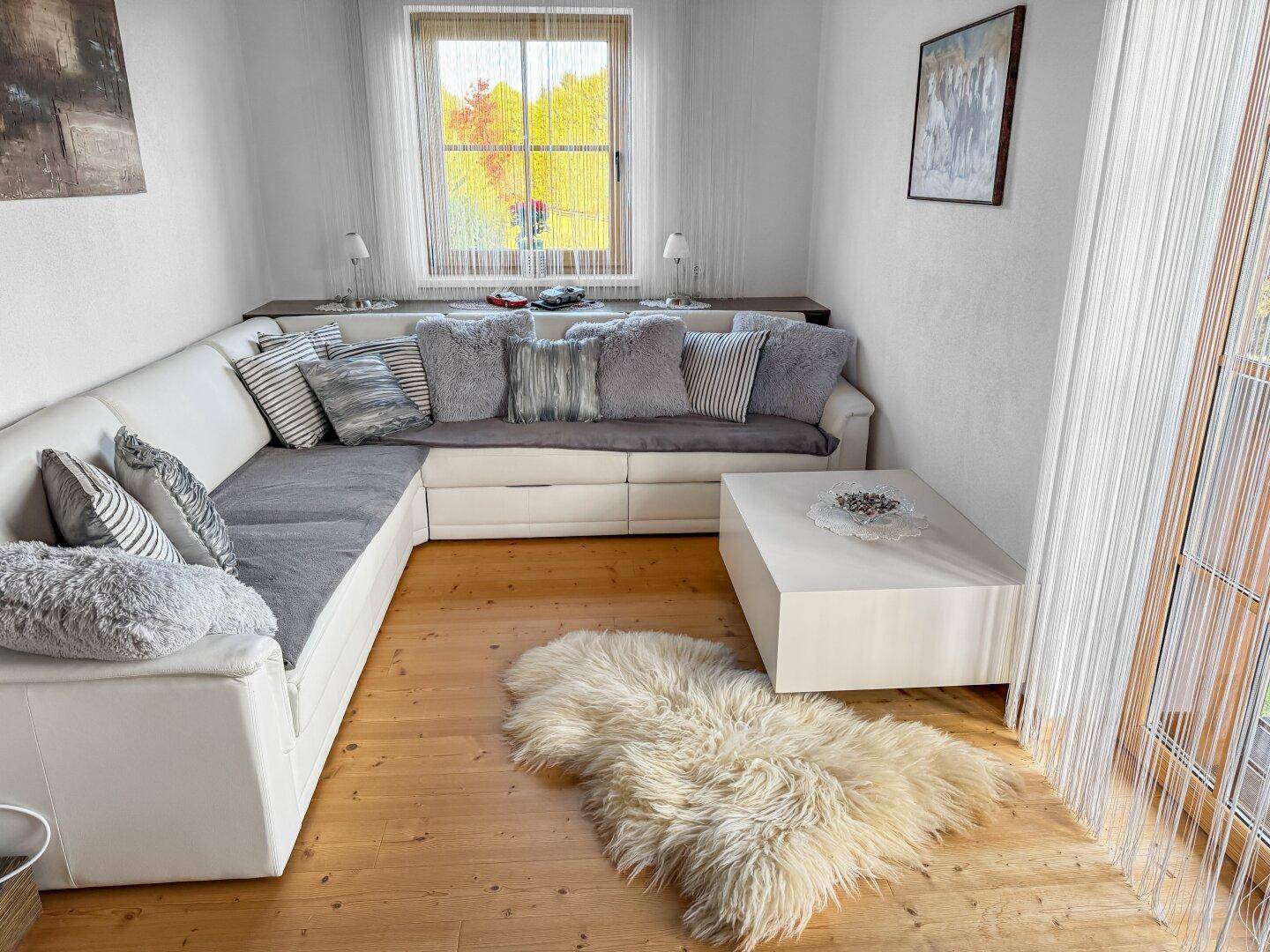 Helles Wohnzimmer mit großem weißen Ecksofa, modernem Couchtisch und flauschigem Teppich.