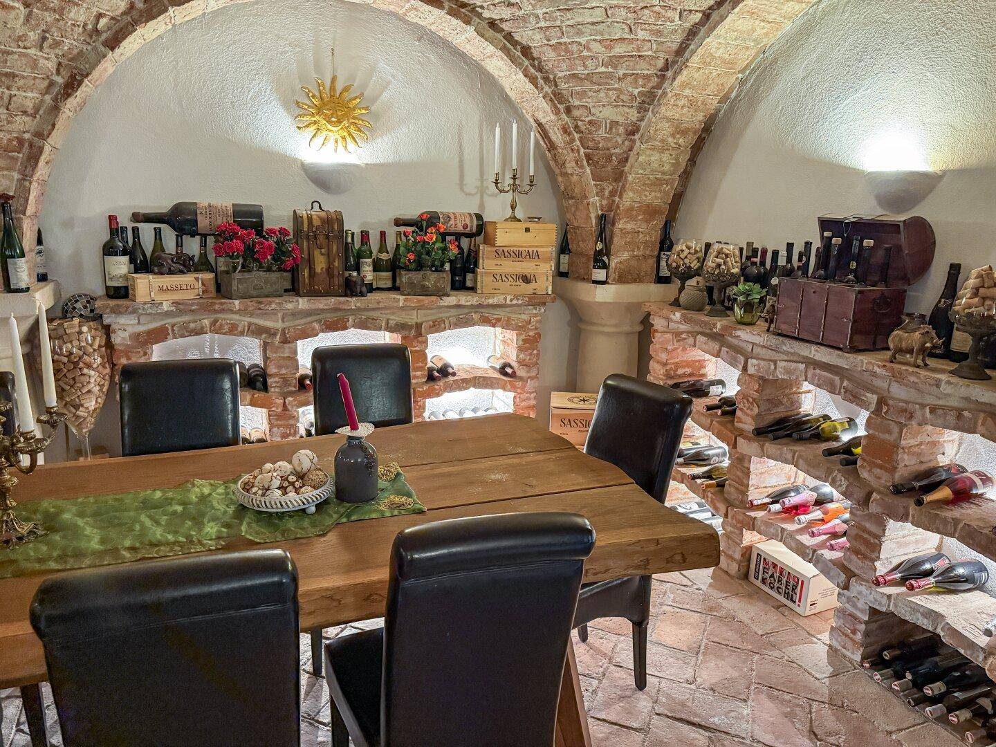 Traditioneller Weinkeller mit langem Holztisch, Ziegelgewölben und Weinlagerung.