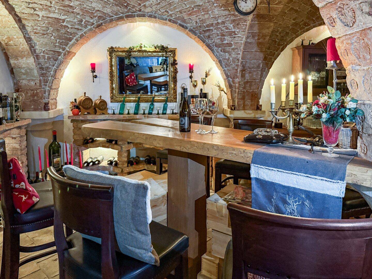 Rustikale Bar in einem Weinkeller mit Ziegelgewölbe, Holztresen und Kerzenlicht.