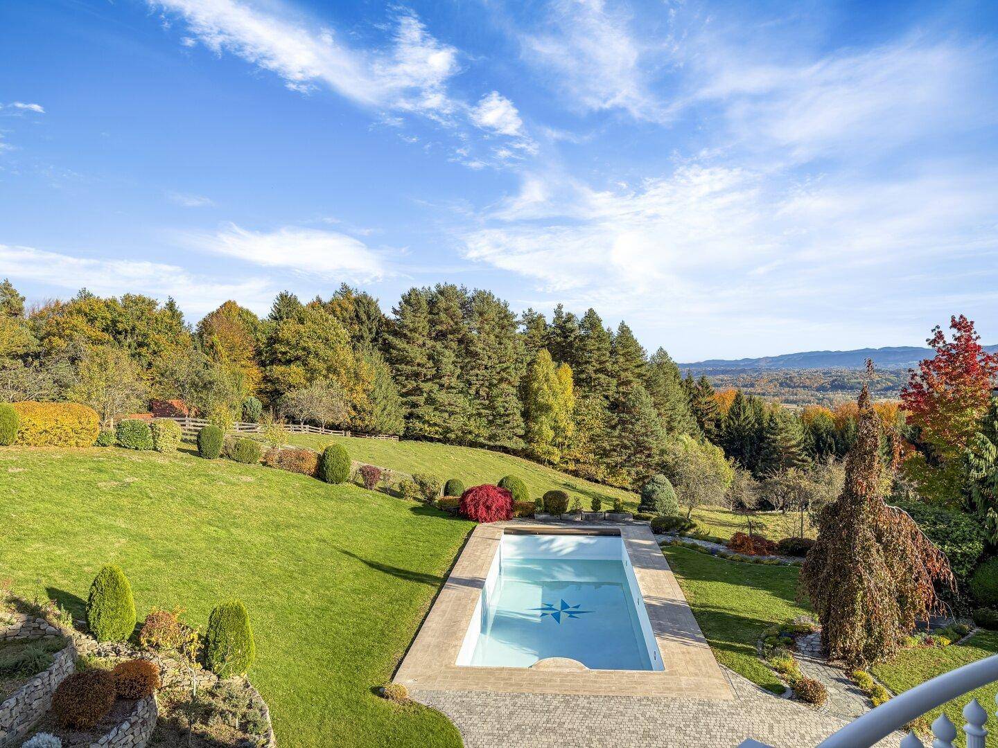 Außenpool in einem gepflegten Garten mit weitem Blick auf die umliegende Landschaft.