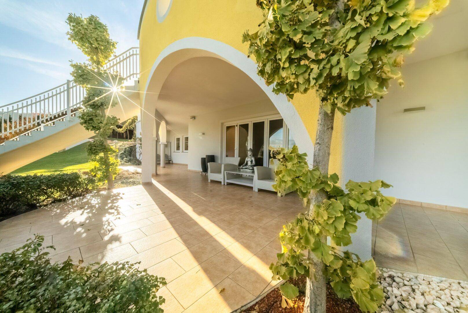 Überdachte Terrasse mit Fliesenboden und Gartenmöbeln, ideal für entspannte Stunden im Freien.
