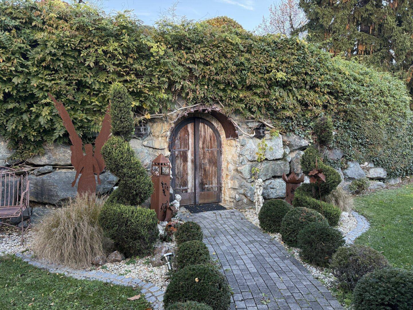 Rustikaler Eingang zum Weinkeller, in den Hang gebaut mit Stein und Grün.