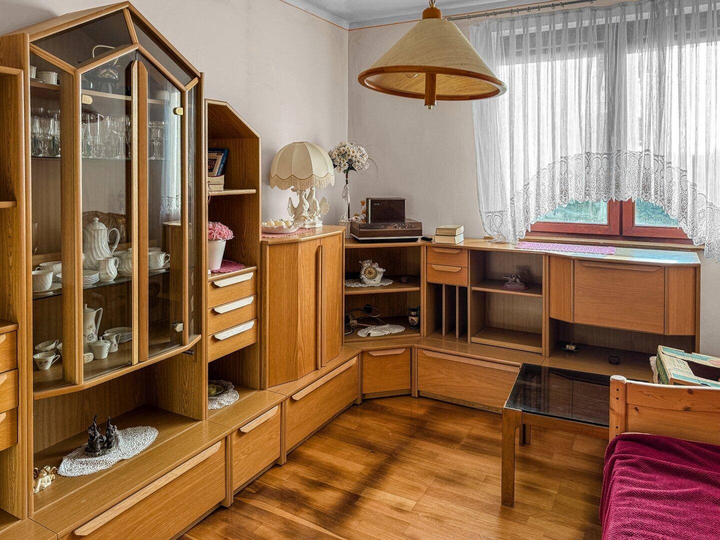 Schlafzimmer mit Holzmöbeln, Parkettboden und einem großen Fenster für viel Tageslicht.