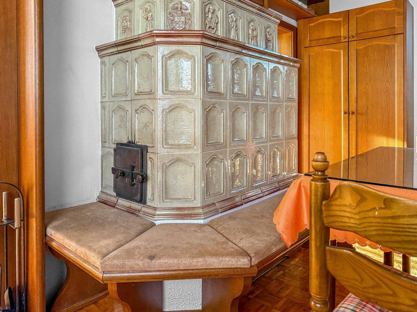Detailansicht eines traditionellen Kachelofens mit Sitzbank, der Wärme und Gemütlichkeit spendet.